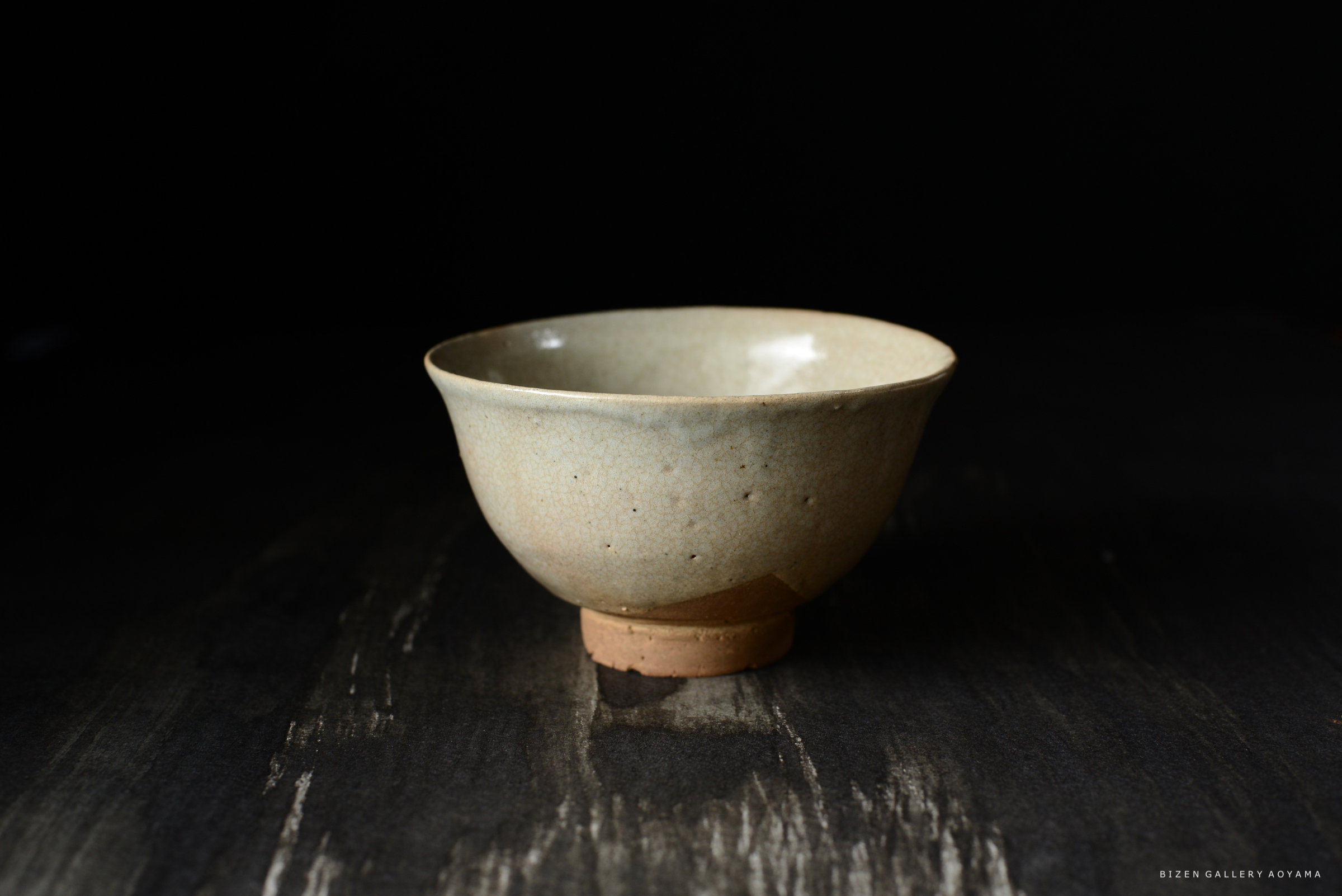 淡い色合いの美しい陶器の茶碗が、暗い背景の上に置かれている。