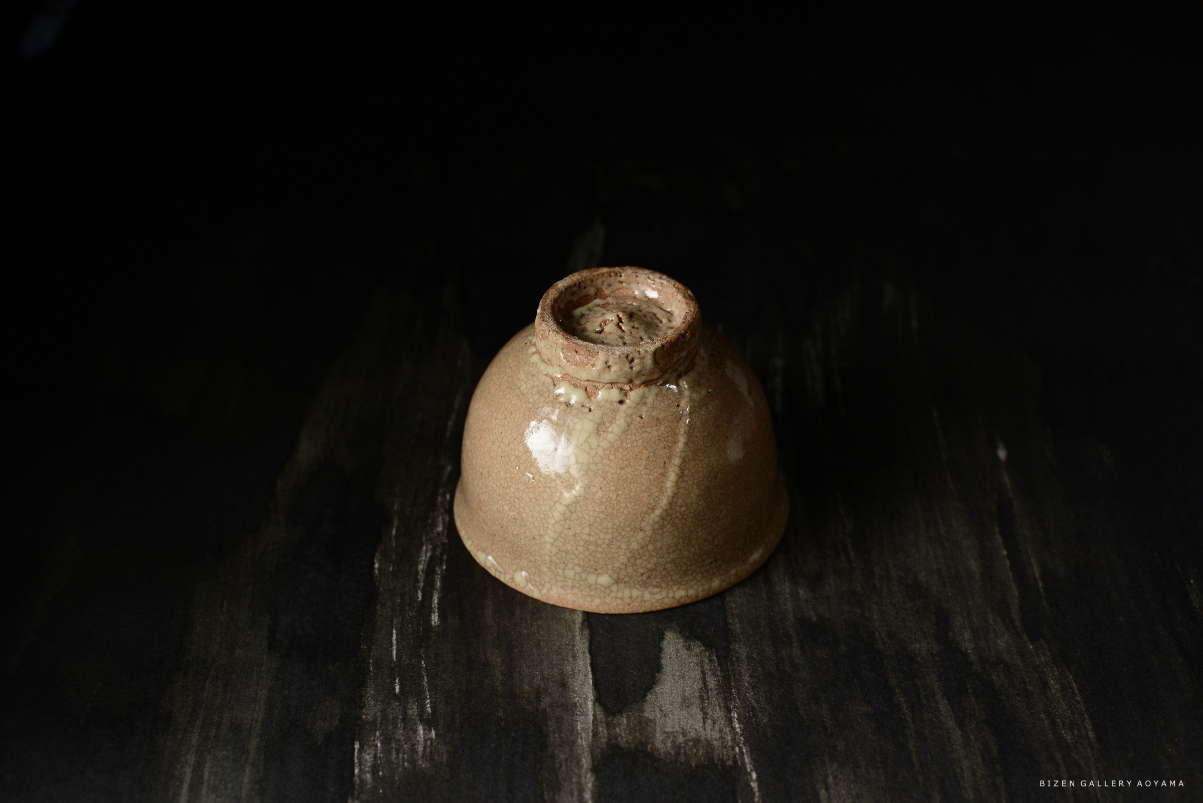 黒い背景の上に置かれた、光沢のある茶色の陶器の器
