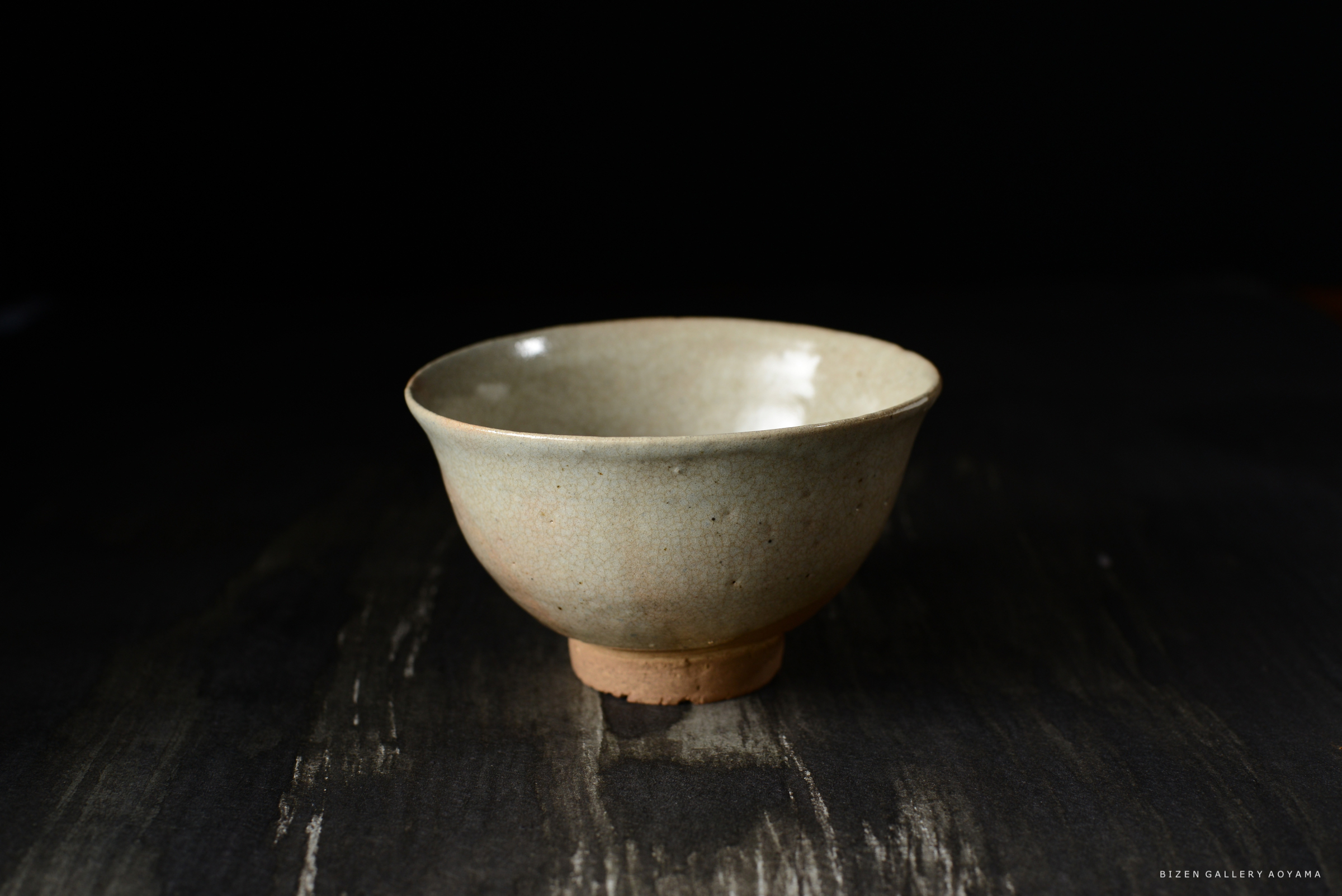 滑らかな質感の陶器の茶碗、浅い形状で底に小さな台座があります。