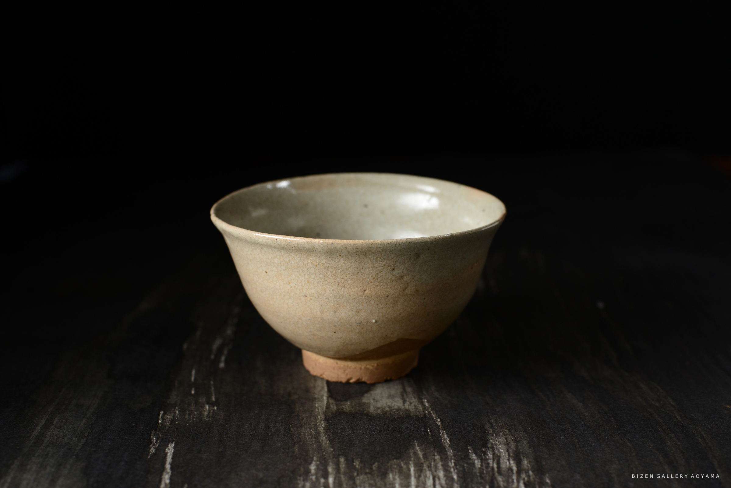 浅い灰色の陶器の茶碗が黒い背景の上に置かれている