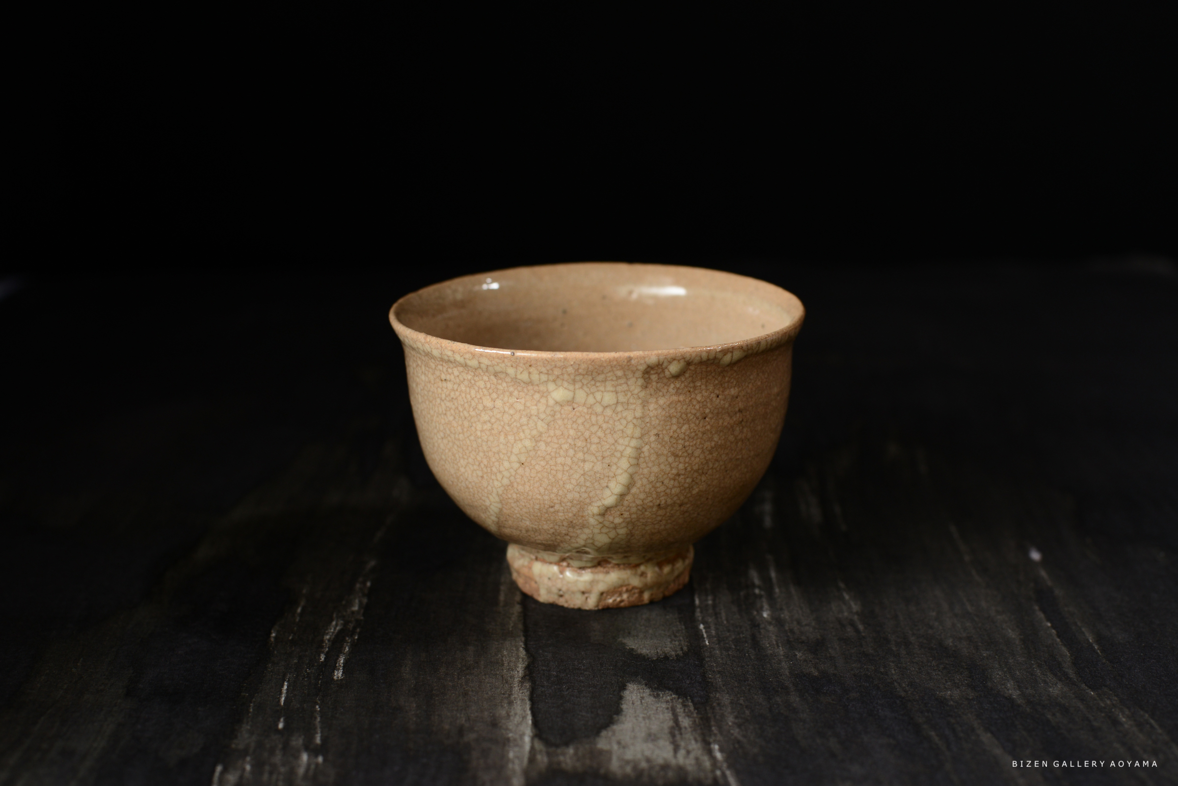 釉薬のひび割れが特徴的な、ビゼン焼の茶碗。淡いベージュ色で、滑らかな質感を持つ。