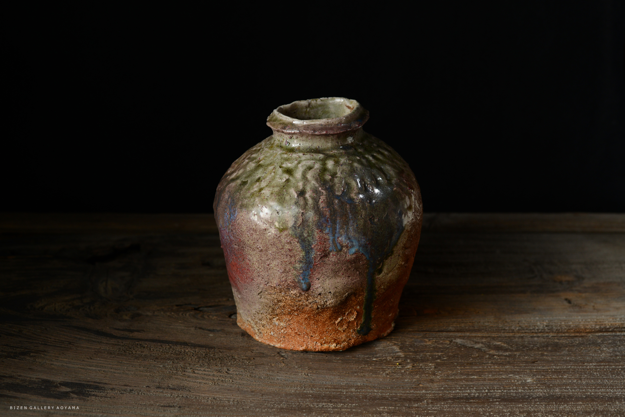 色彩豊かな陶器の壺、地面に置かれ、黒い背景で際立つ