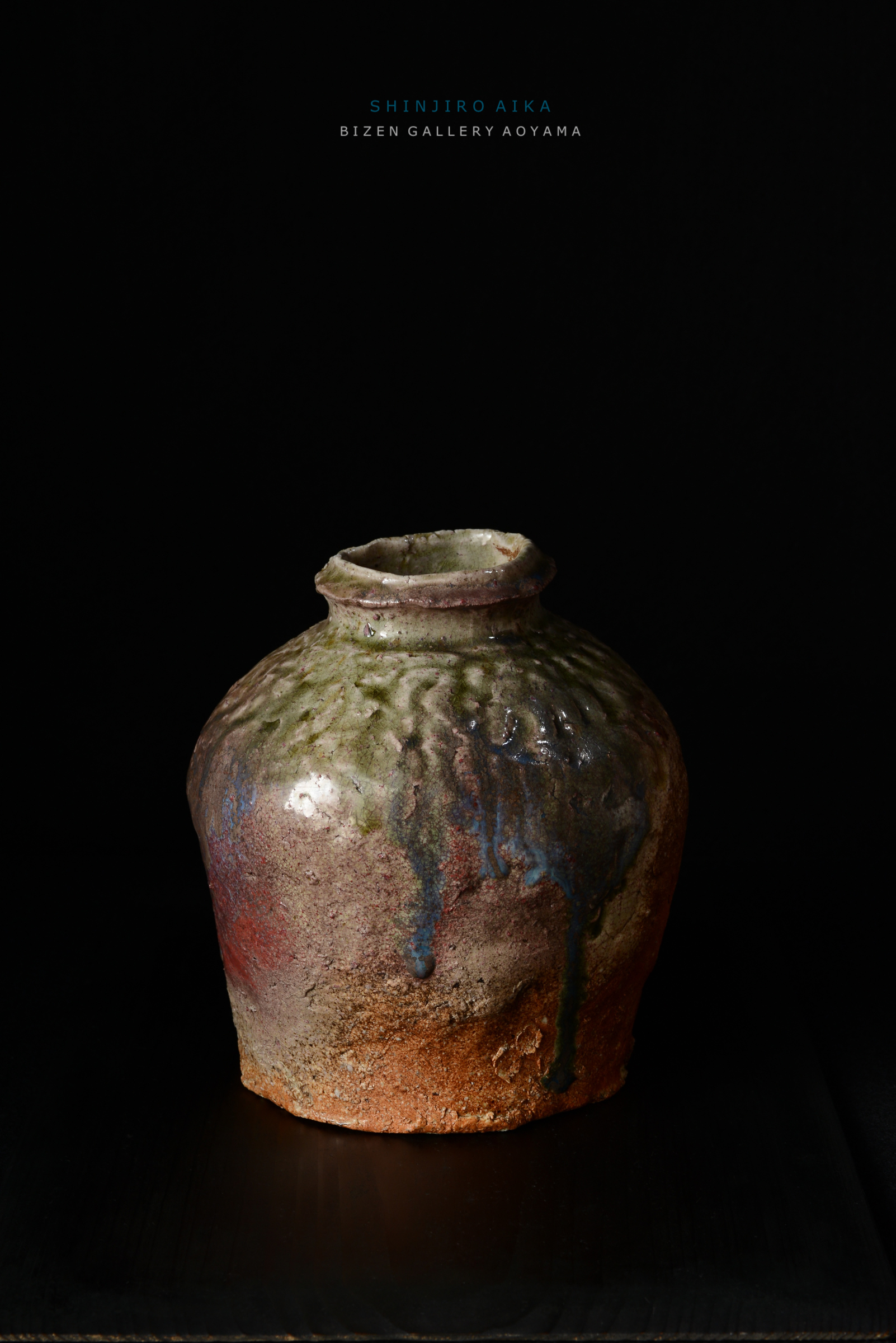 黒い背景の前に置かれた独特の形状を持つ陶器の壺。壺の表面には色とりどりの釉薬が施されている。