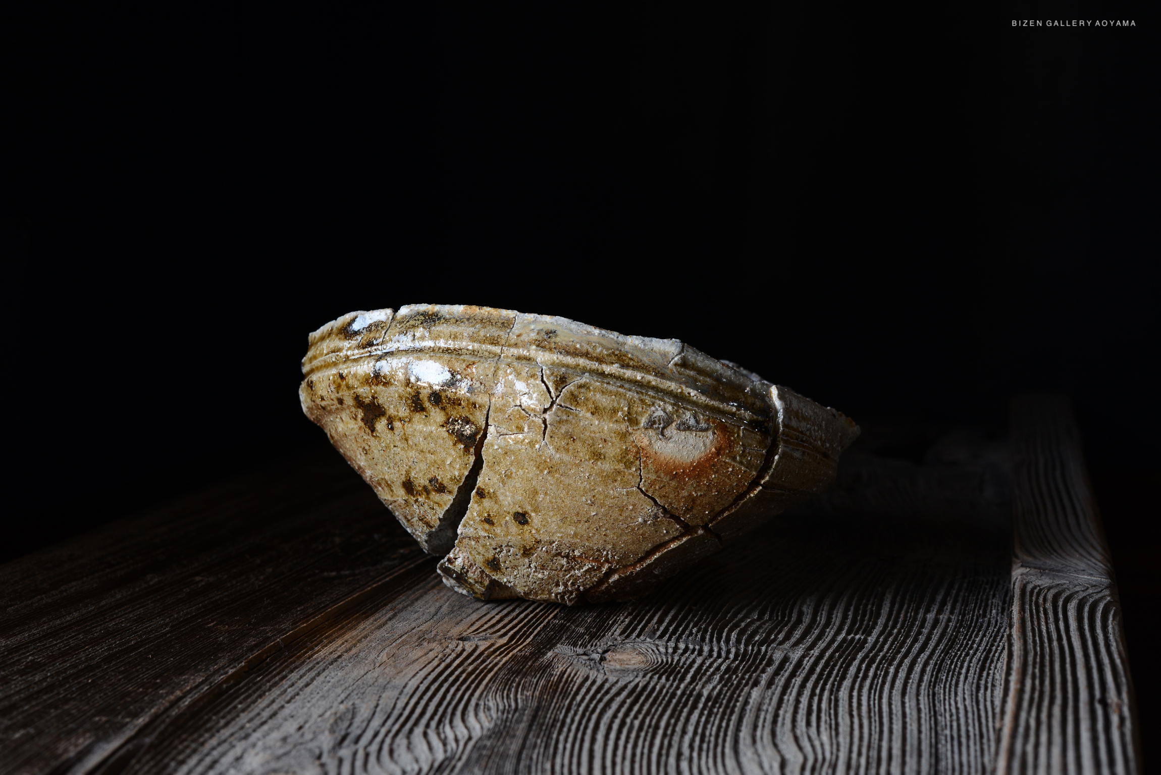 割れた古い陶器の鉢が暗い背景の上に置かれている画像