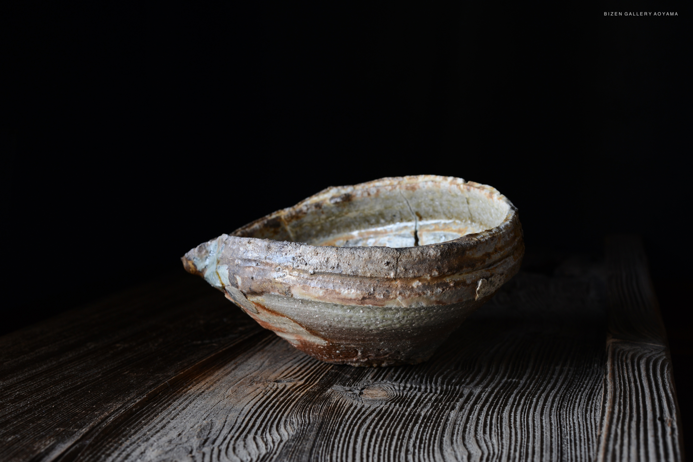 木製のテーブルの上に置かれた、手作りの独特な形をした陶器のボウル