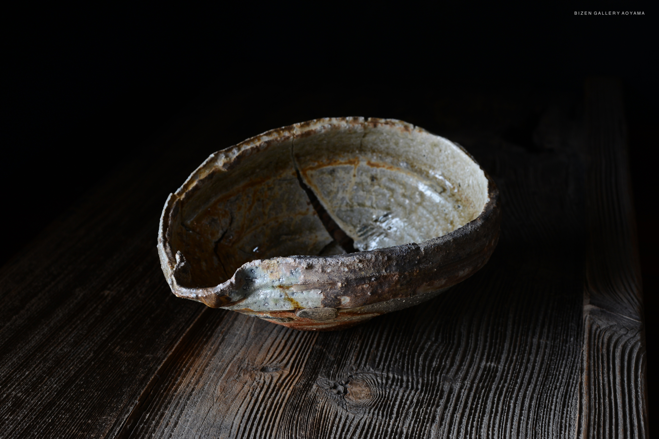 古い和風の陶器の鉢が木製のテーブルの上に置かれている。