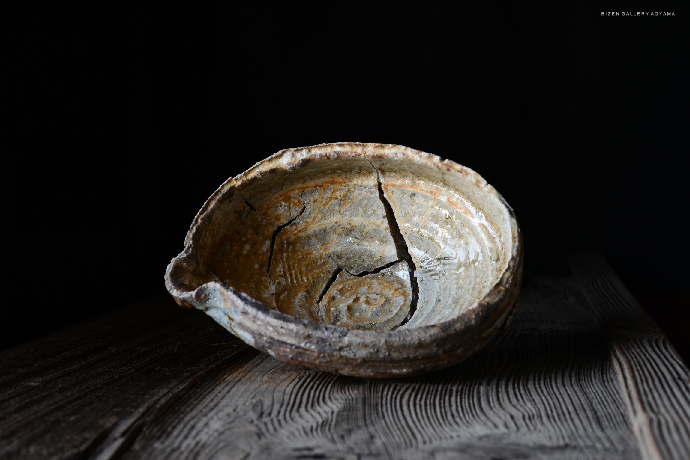 黒い背景の前に置かれたひび割れた陶器の皿。