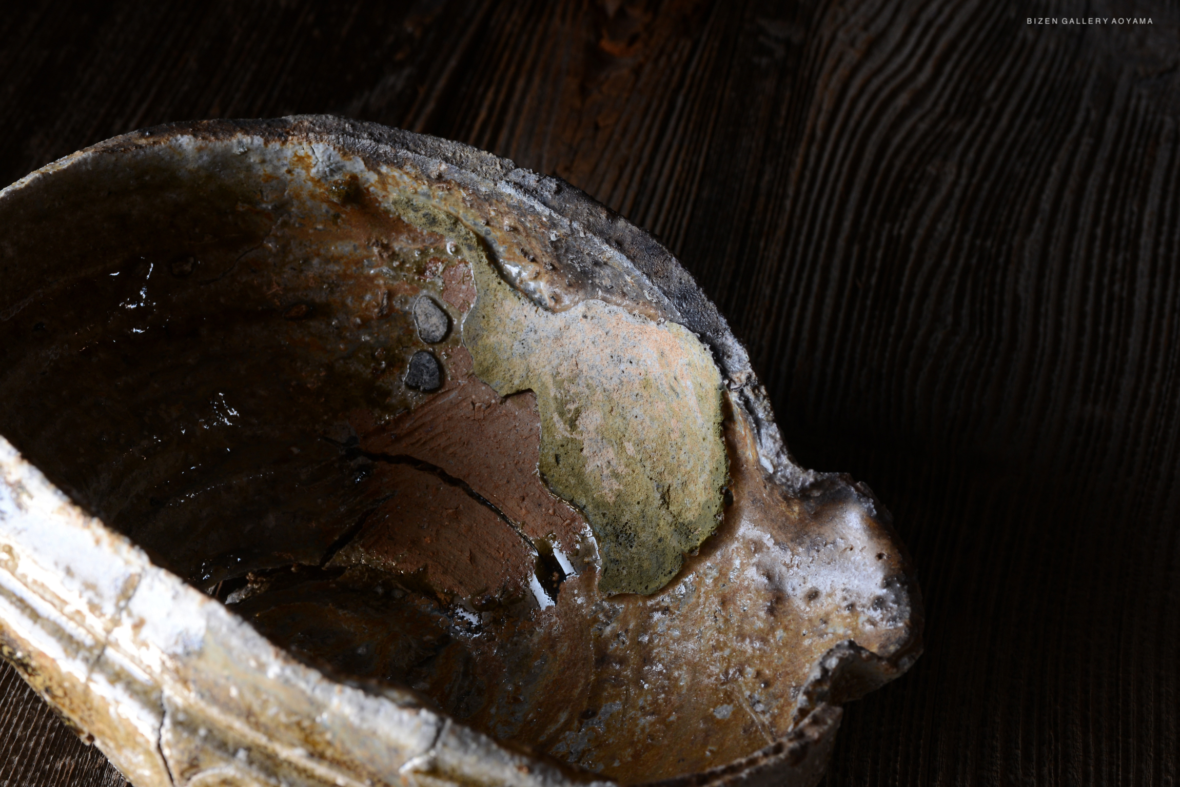 古い陶器の内部を映した画像。色合いが異なる部分があり、水が少したまっている。