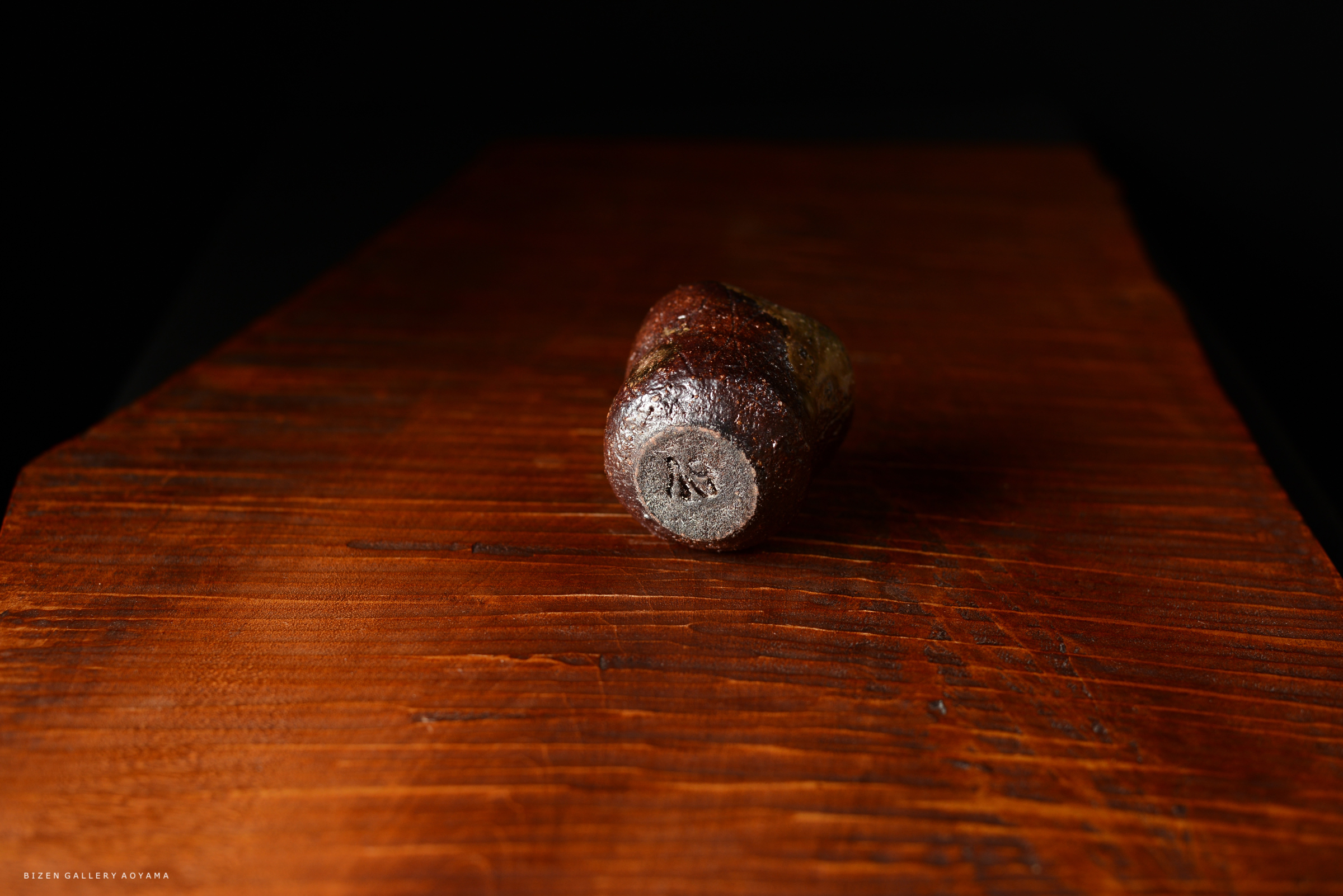 木製のテーブルの上に置かれた陶器の作品の底面