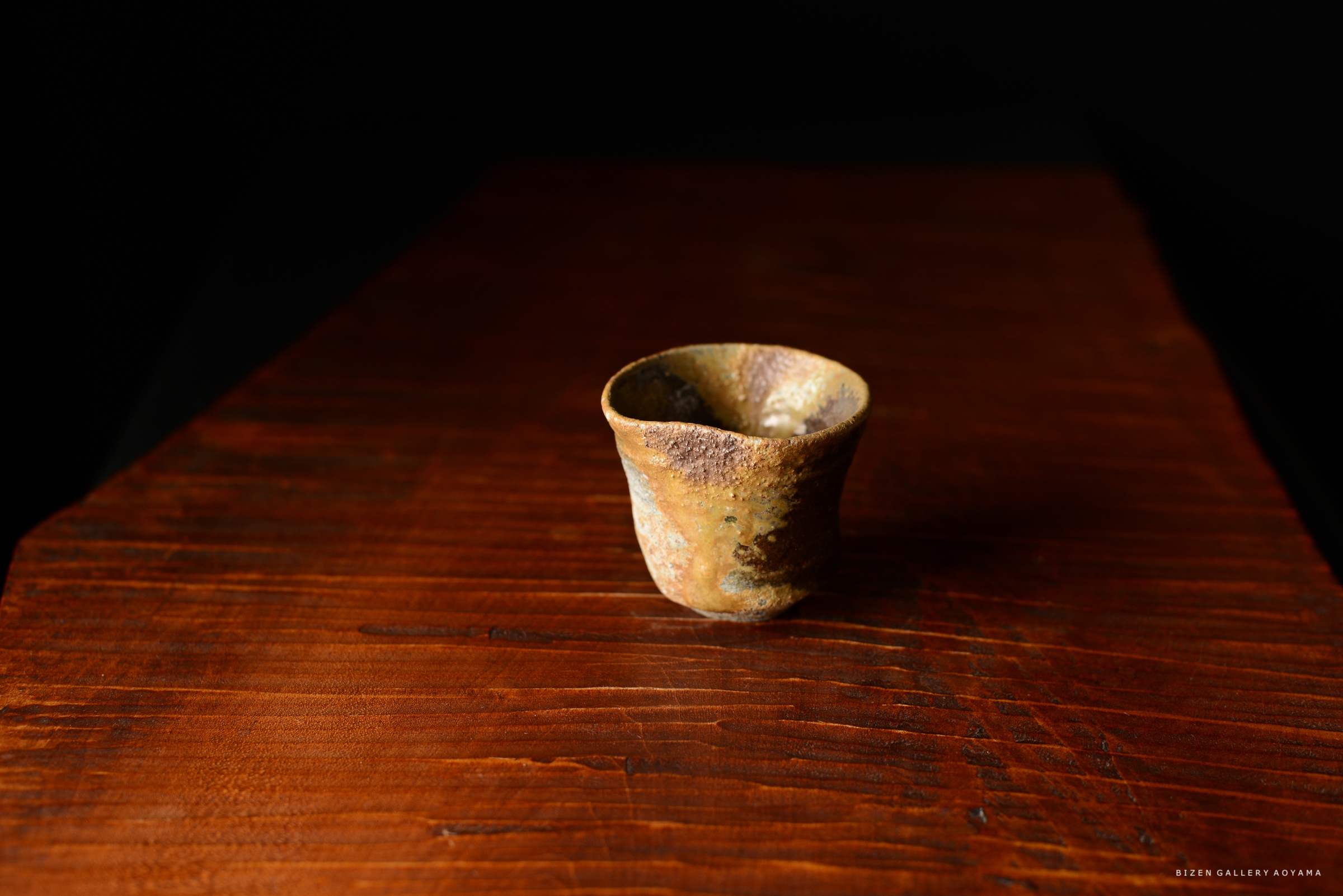 暗い背景の上に置かれた、独特な形の陶器のカップ