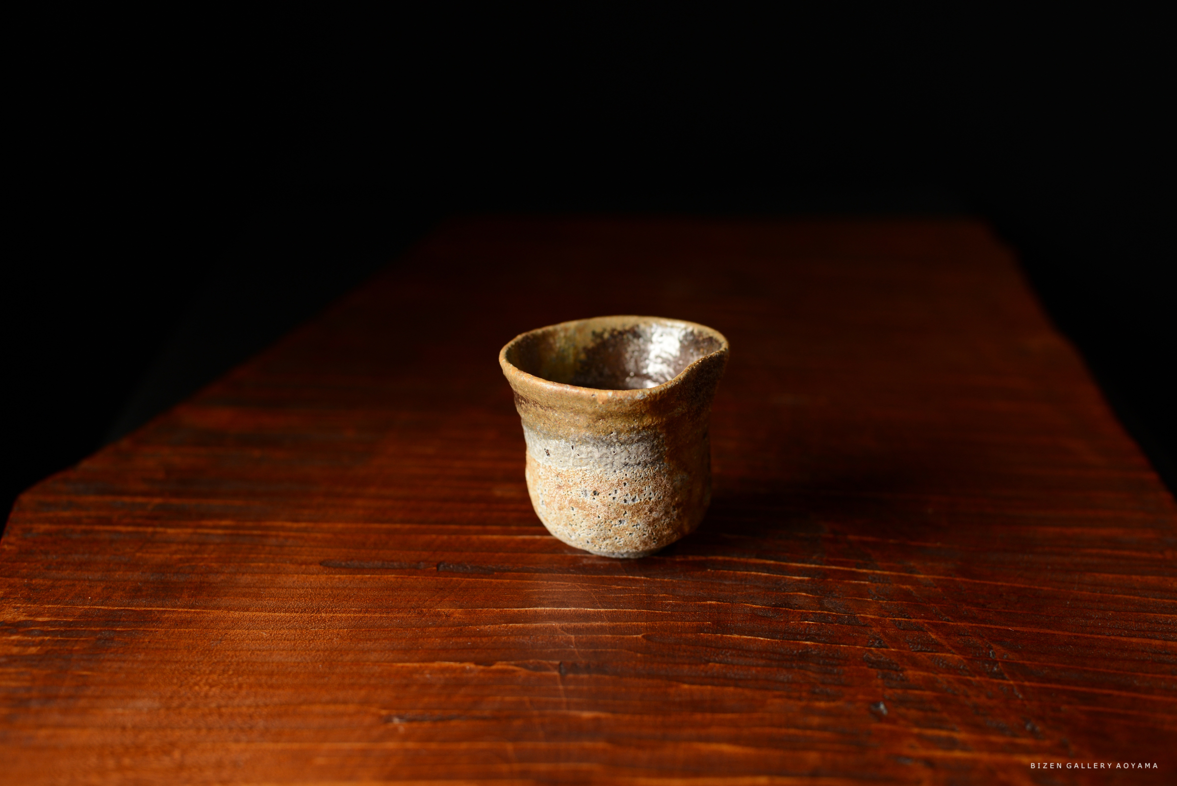 木製のテーブルの上に置かれた、素焼きの焼き物の湯呑み