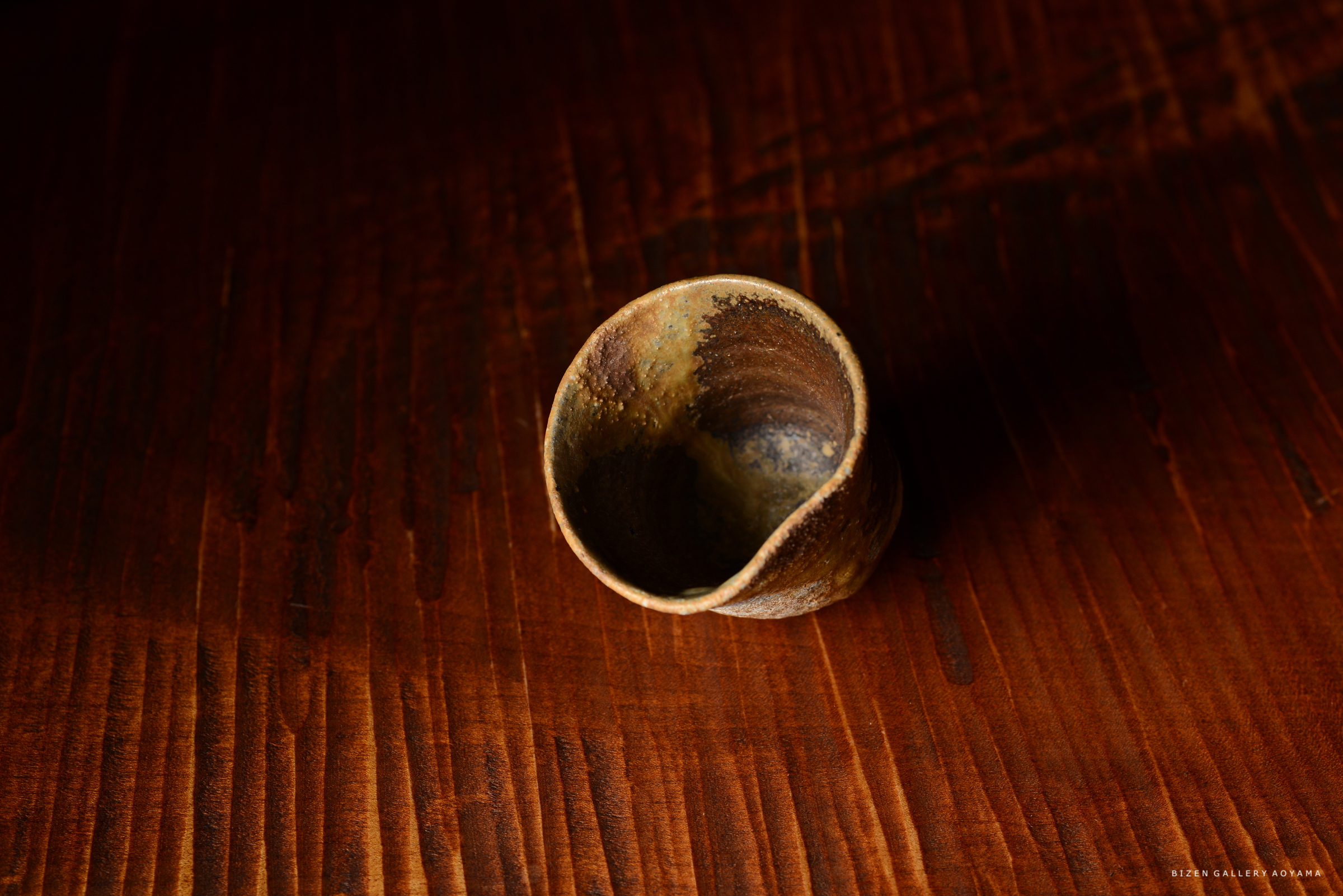 木製のテーブルの上に置かれた独特な形の陶器のカップ。