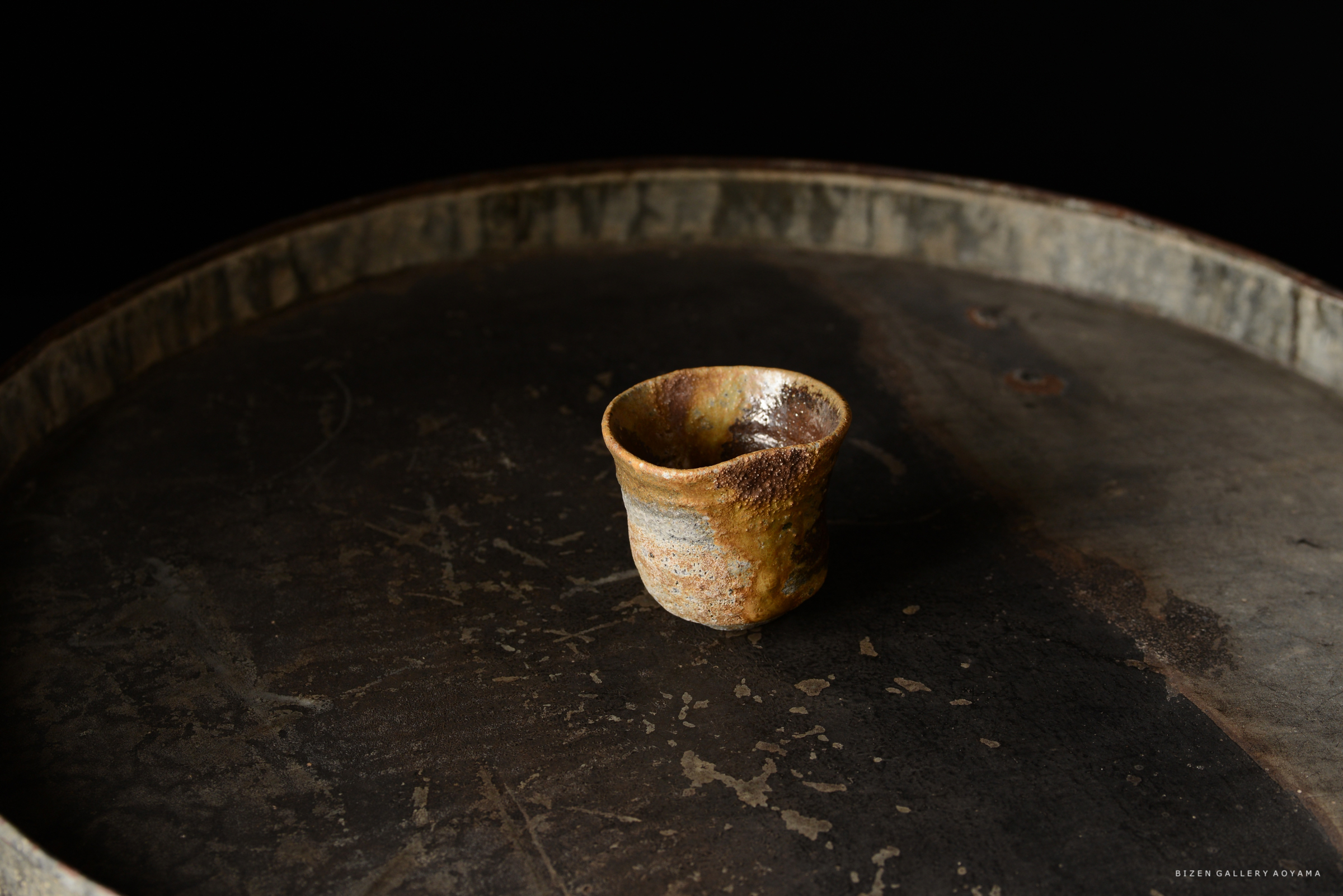 黒い背景の上に置かれた手作りの陶器のカップ。