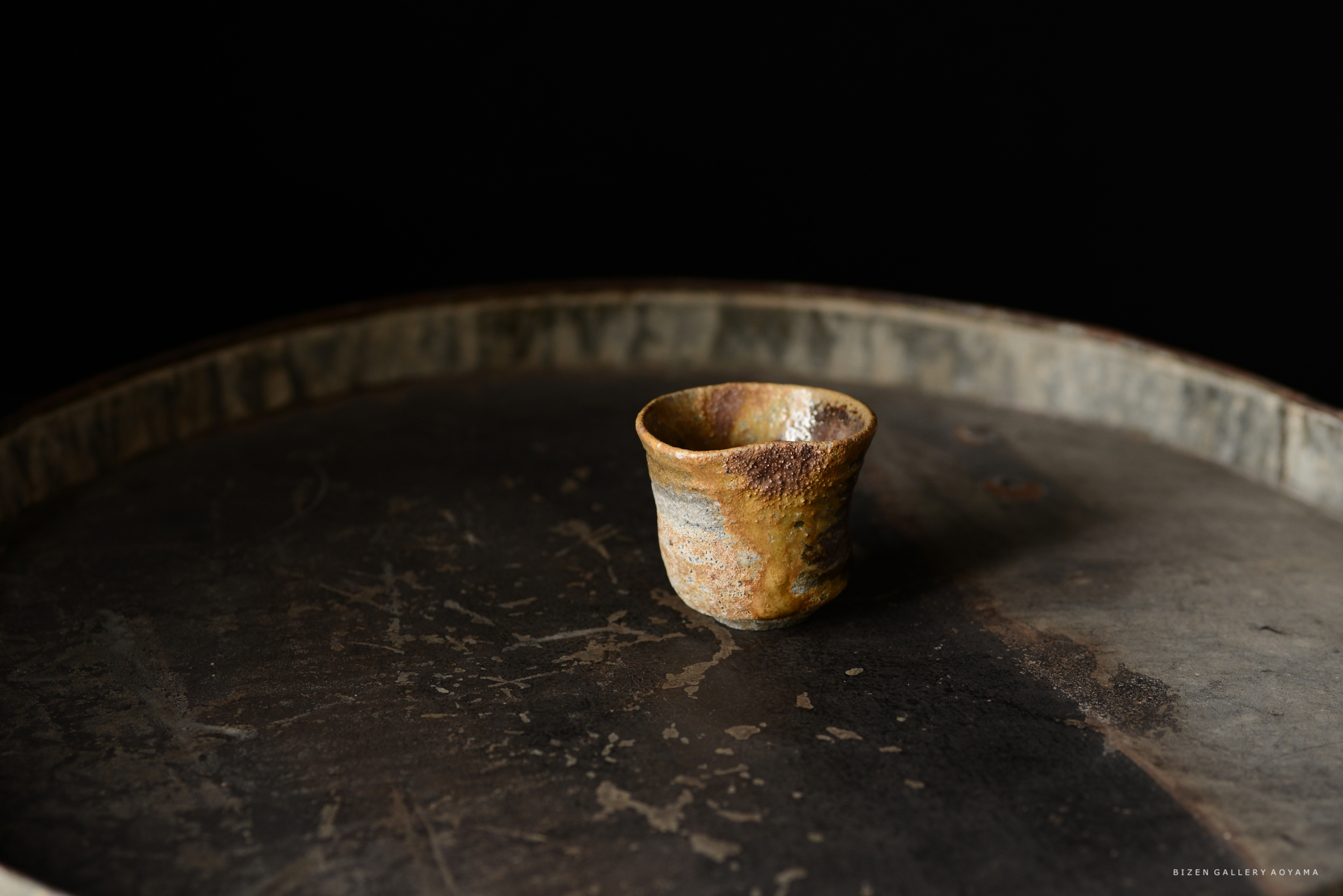 黒い背景の上に置かれた独特な形状の陶器のカップ。