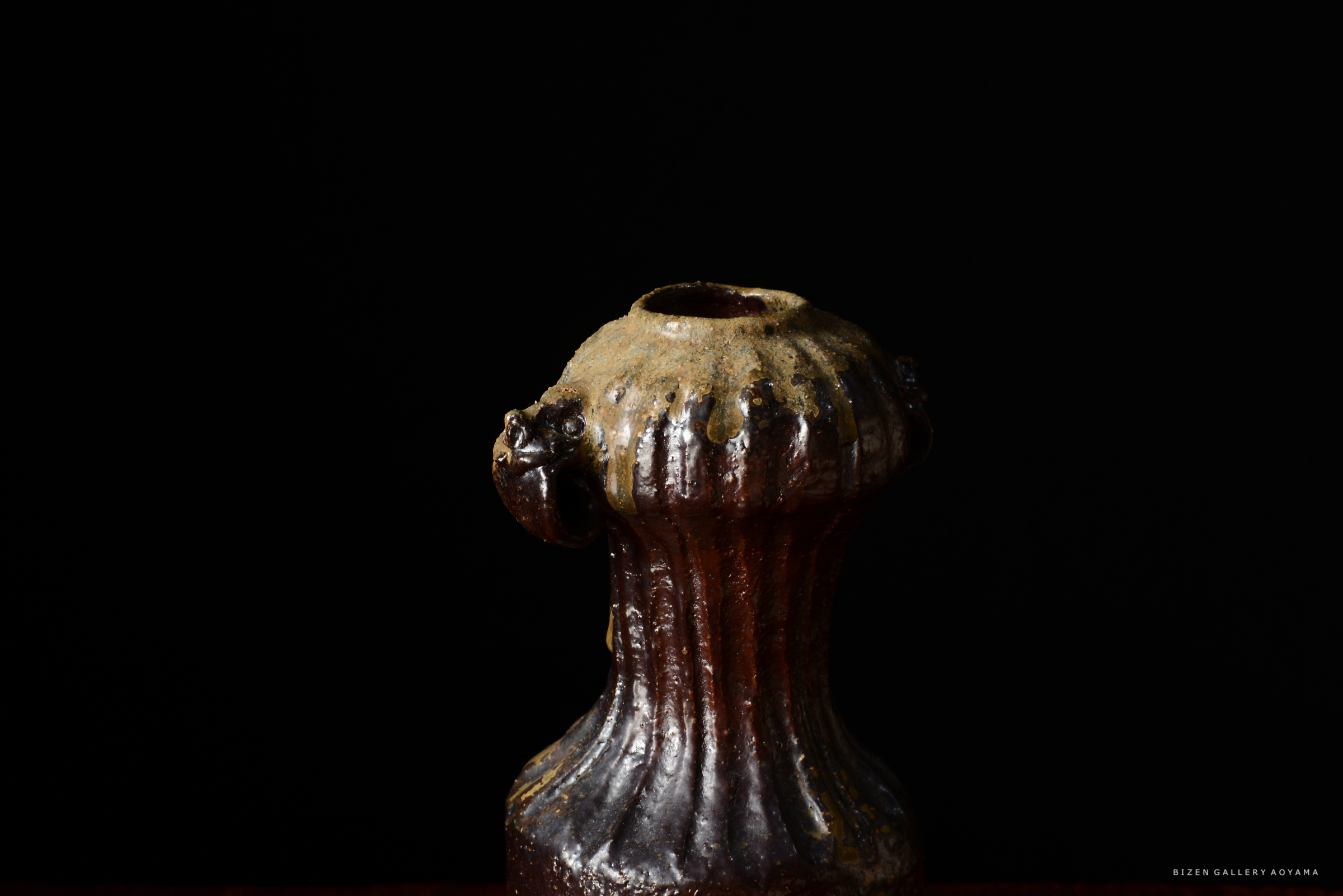 黒い背景にある独特な形状の陶器の壺。