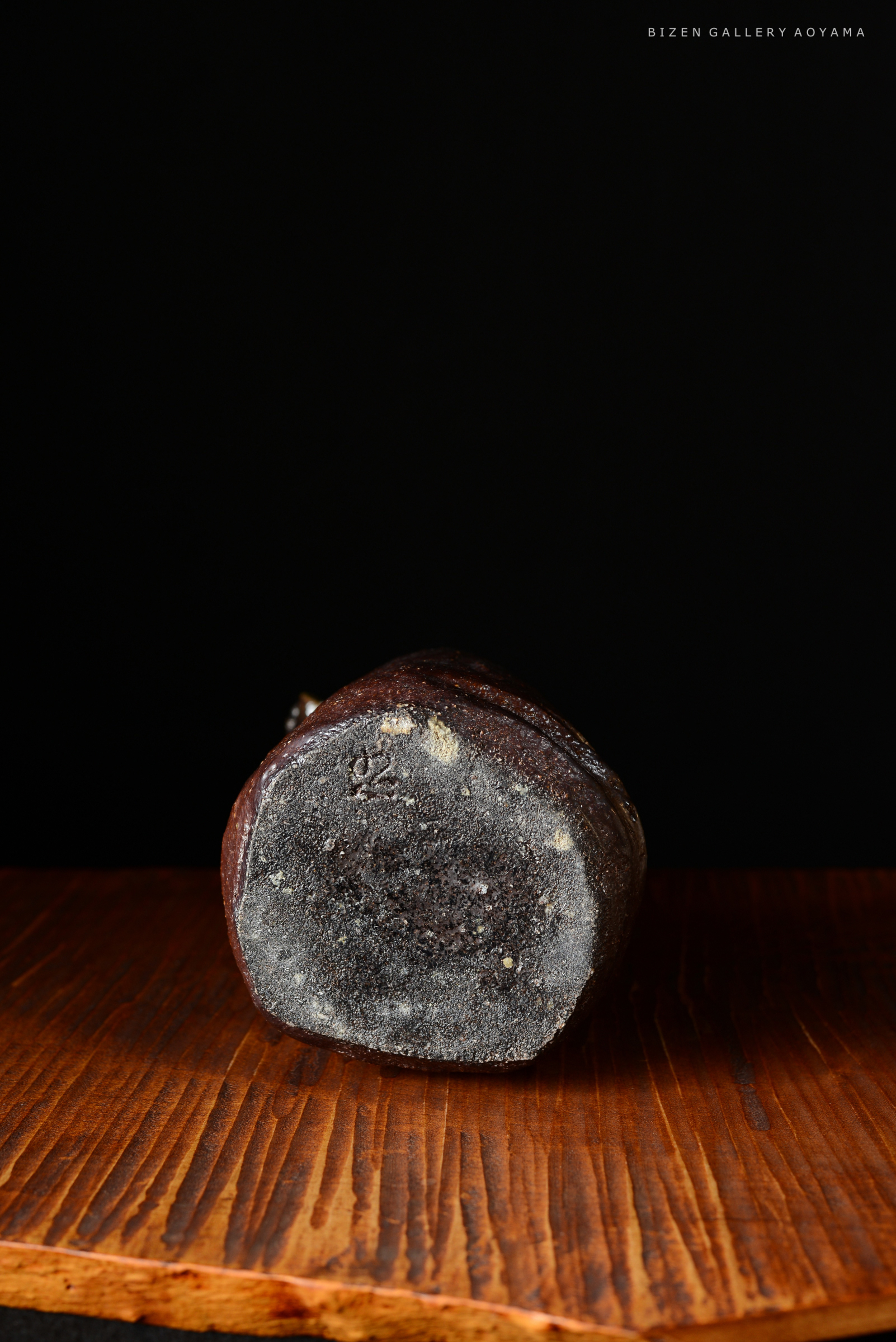 黒い背景に置かれた陶器の底面。木製のテーブルに置かれ、表面には細かい模様が見える。