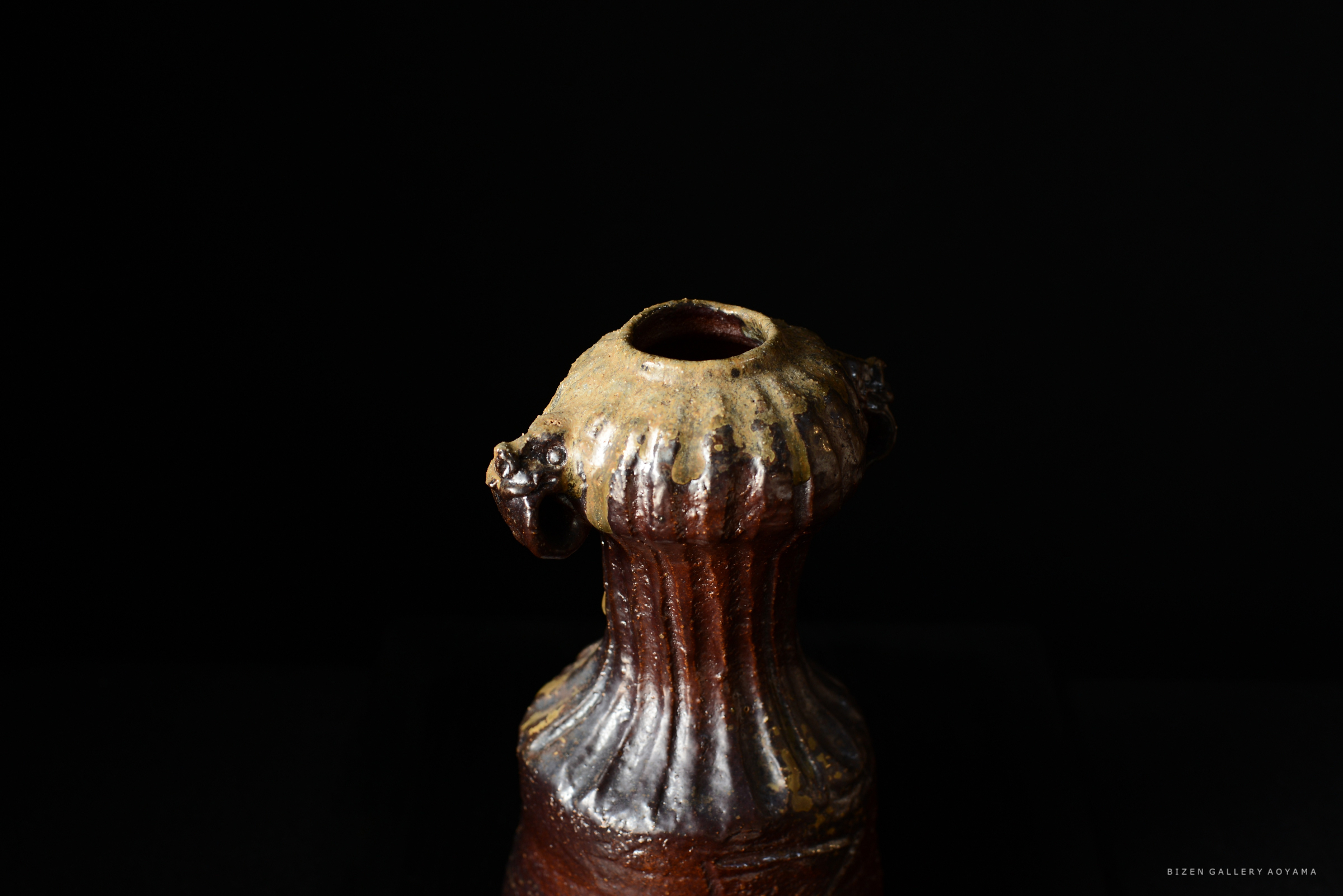 黒い背景の前に置かれた美しい陶器。独特な形状と色合いが特徴。