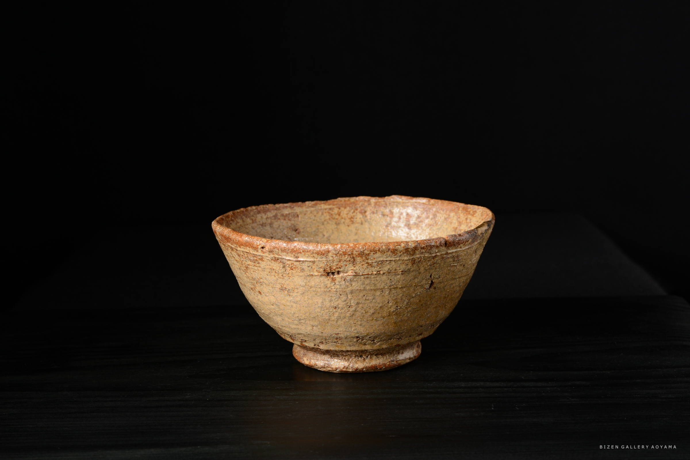 黒い背景の前に置かれた茶色の陶器の碗