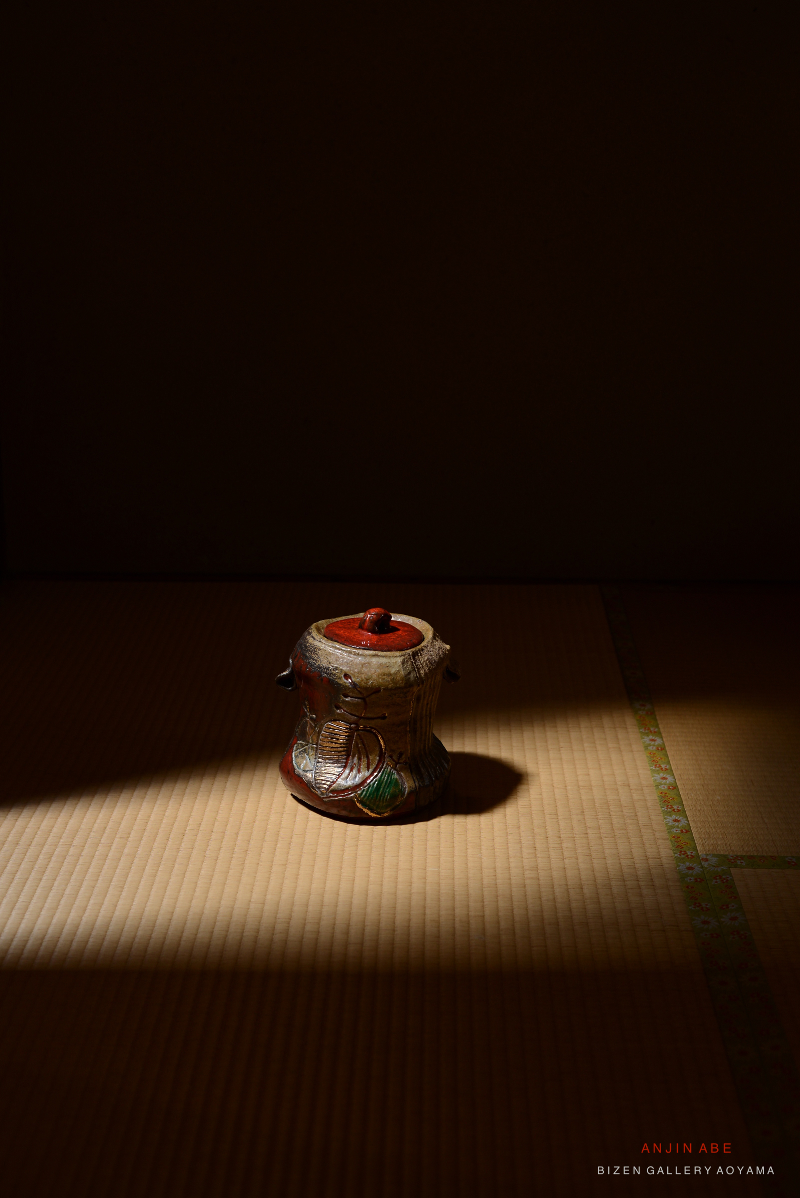 和室の畳の上に置かれた装飾された陶器の容器。柔らかな光が当たっている。