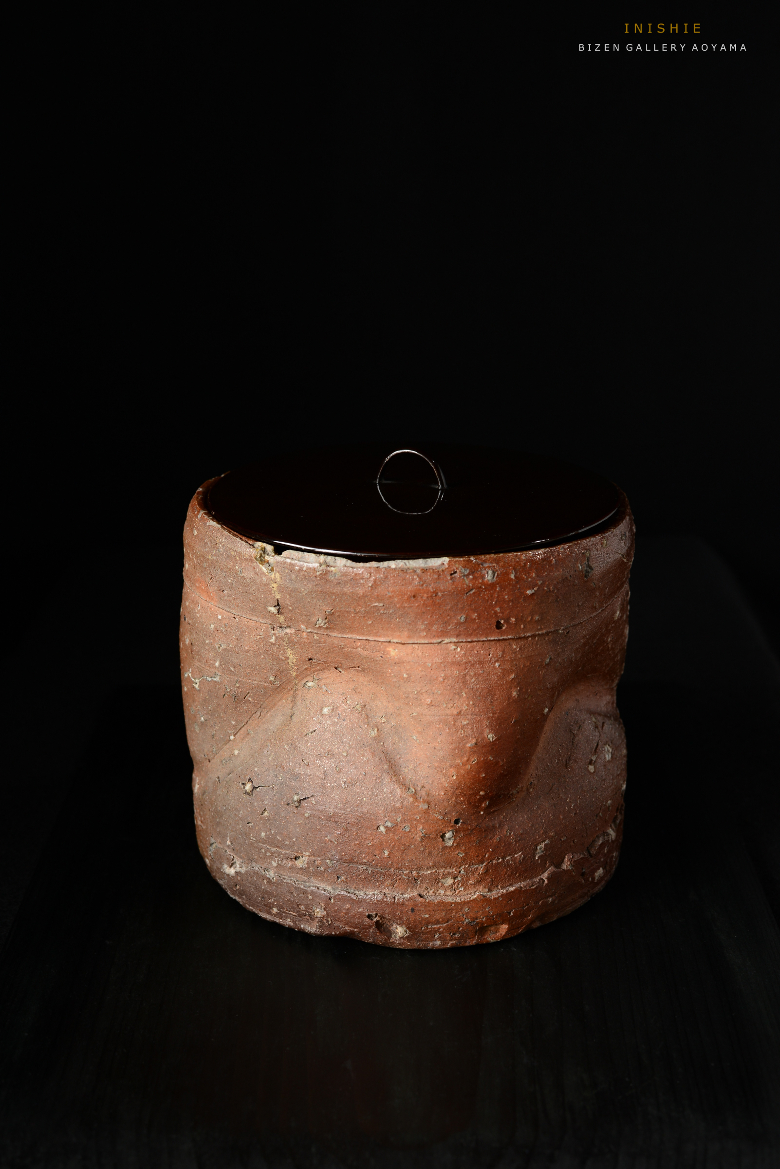 光沢のある黒い蓋を持つ、赤土で作られた陶器の容器