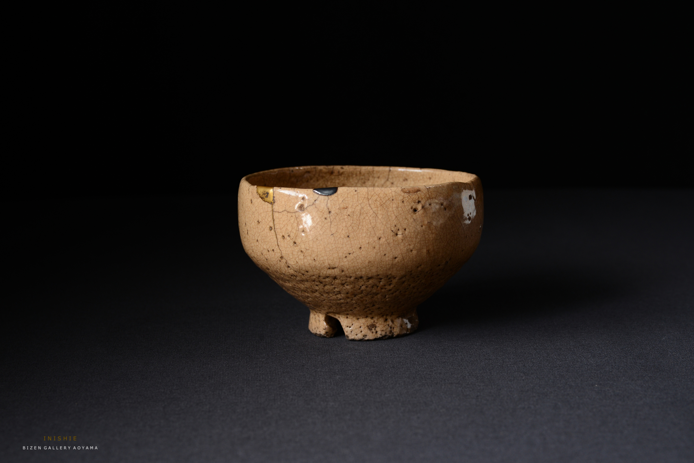 黒い背景の前に置かれた、独特な質感の土で作られた茶碗。