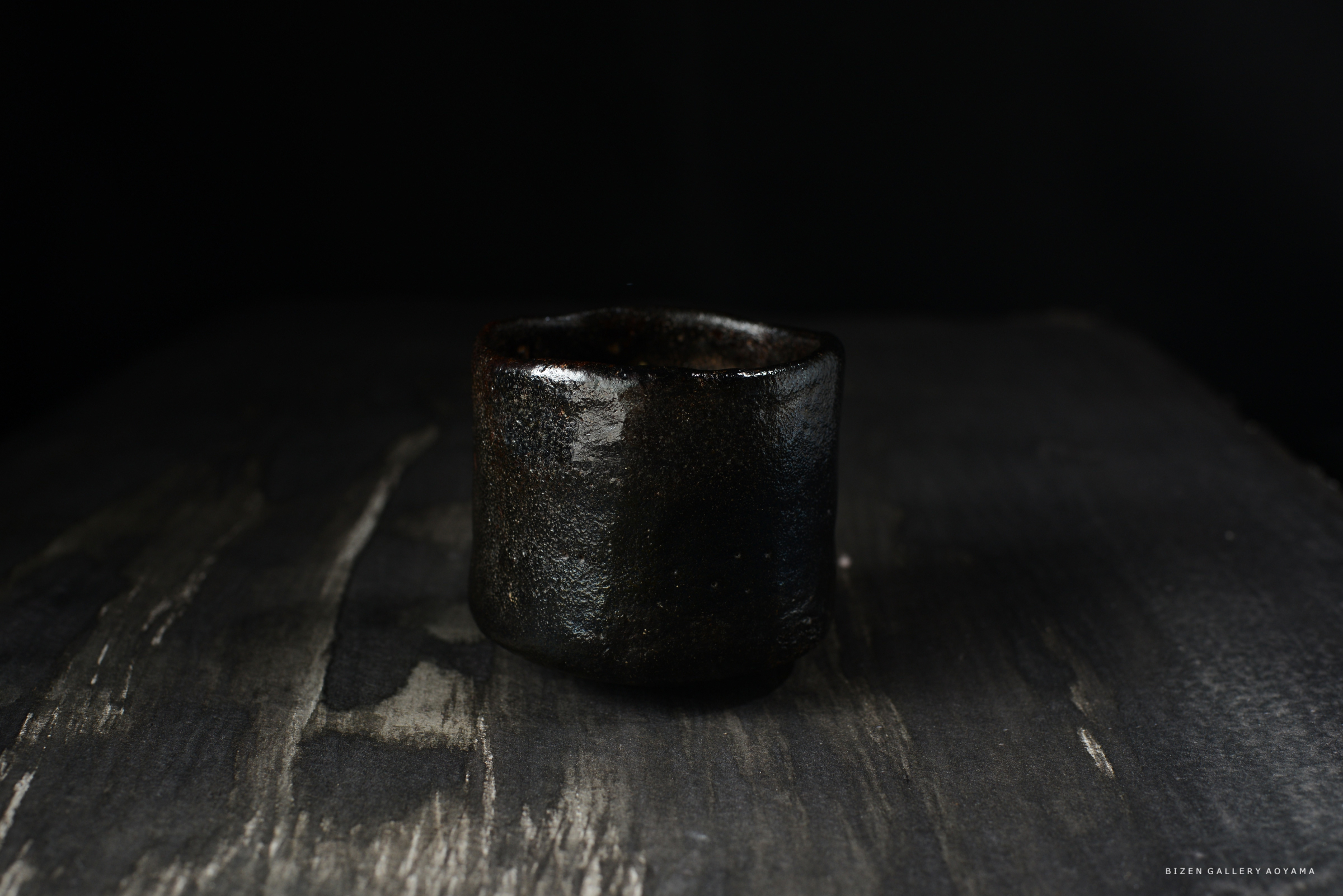 黒い陶器の茶碗が暗い背景の上に置かれている