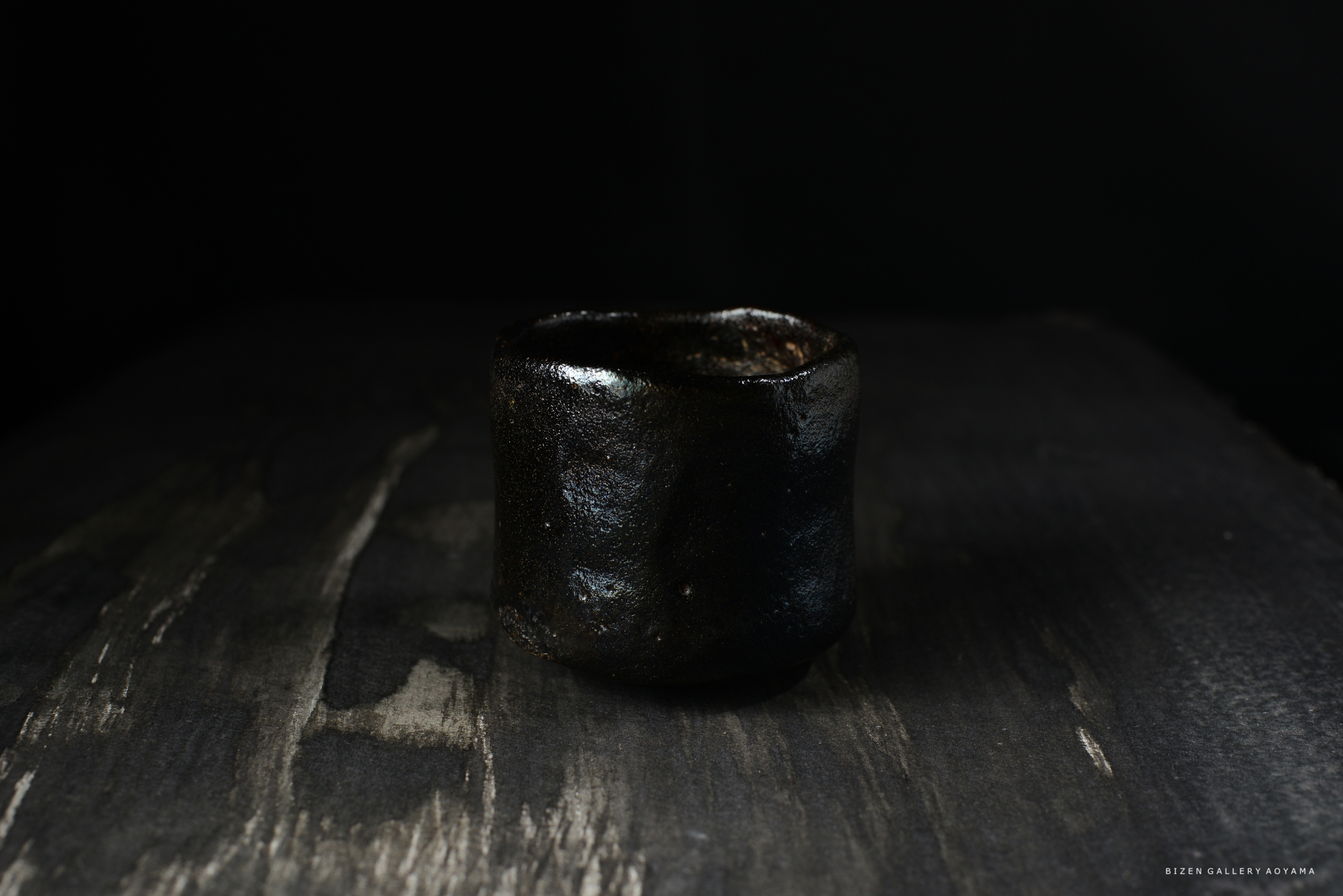 黒い陶器の茶碗が暗い背景の上に置かれている。