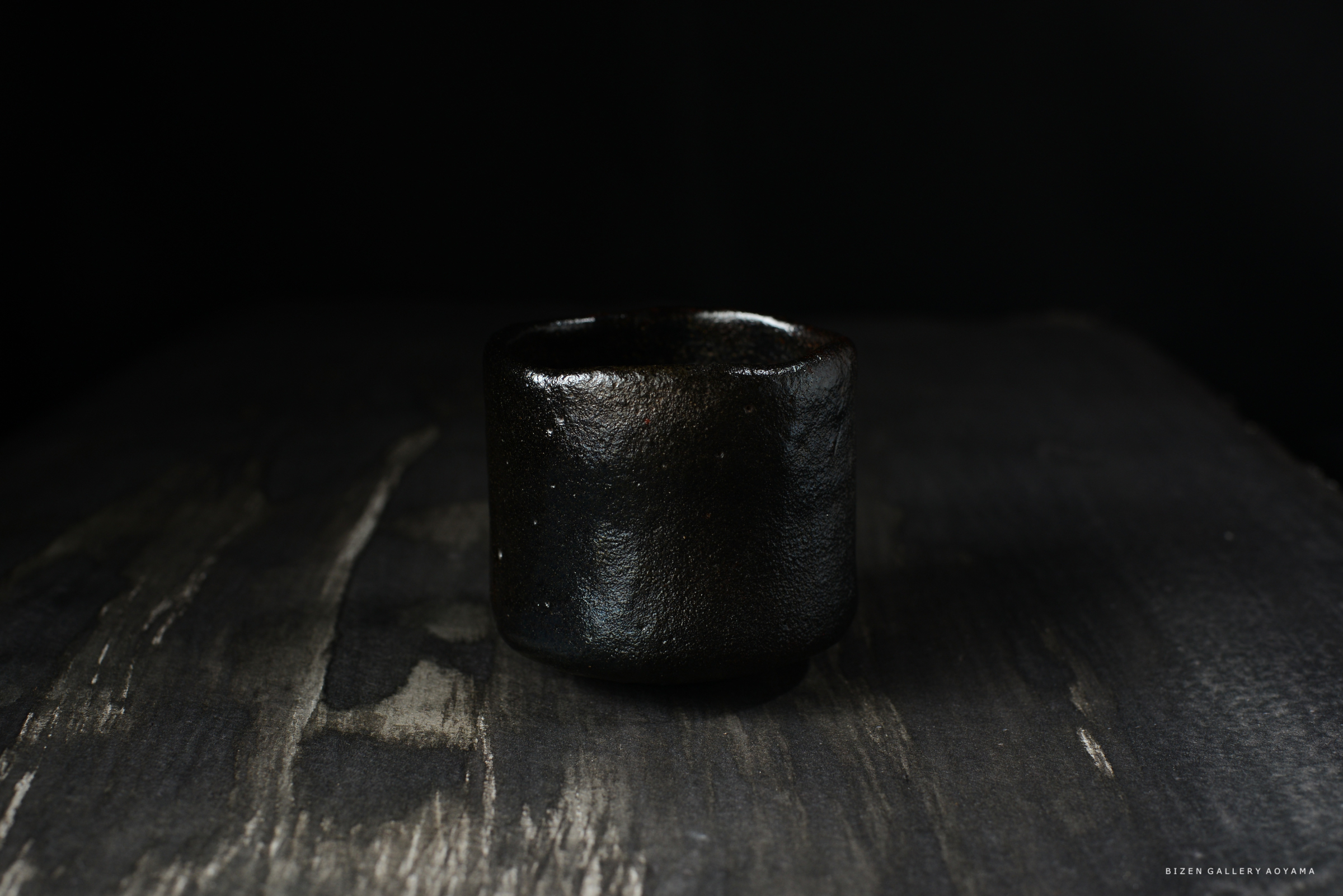 黒い陶器の容器が暗い背景の上に置かれている画像