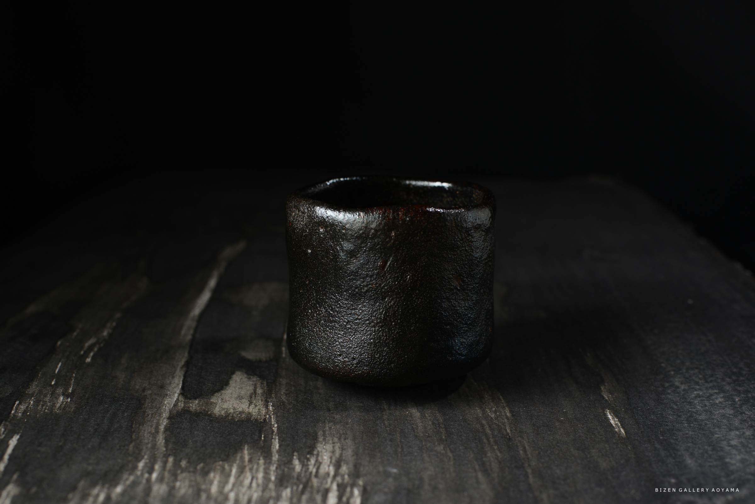 黒い陶器の茶碗が暗い背景の上に置かれている画像