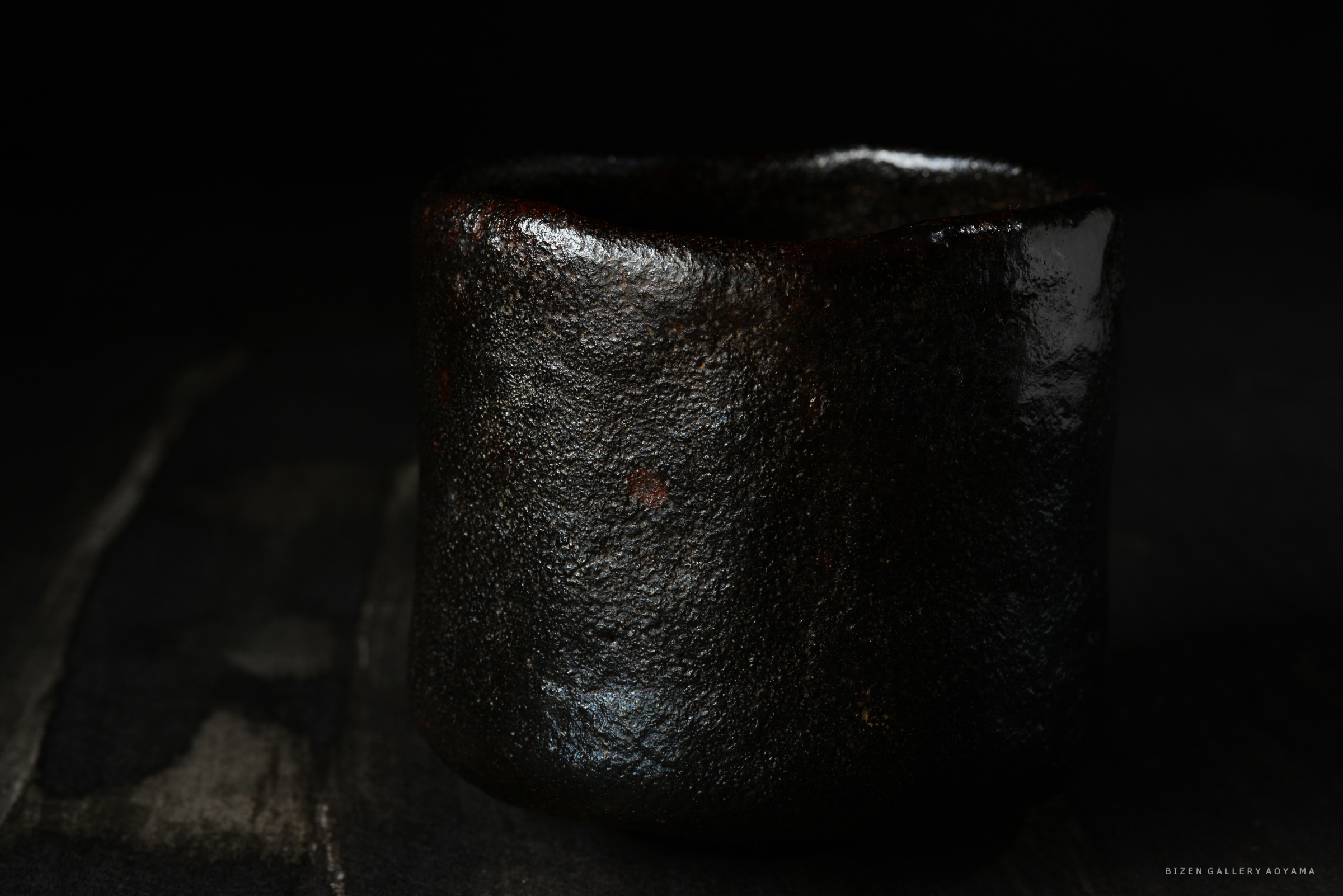 黒い陶器の茶碗が暗い背景に置かれている