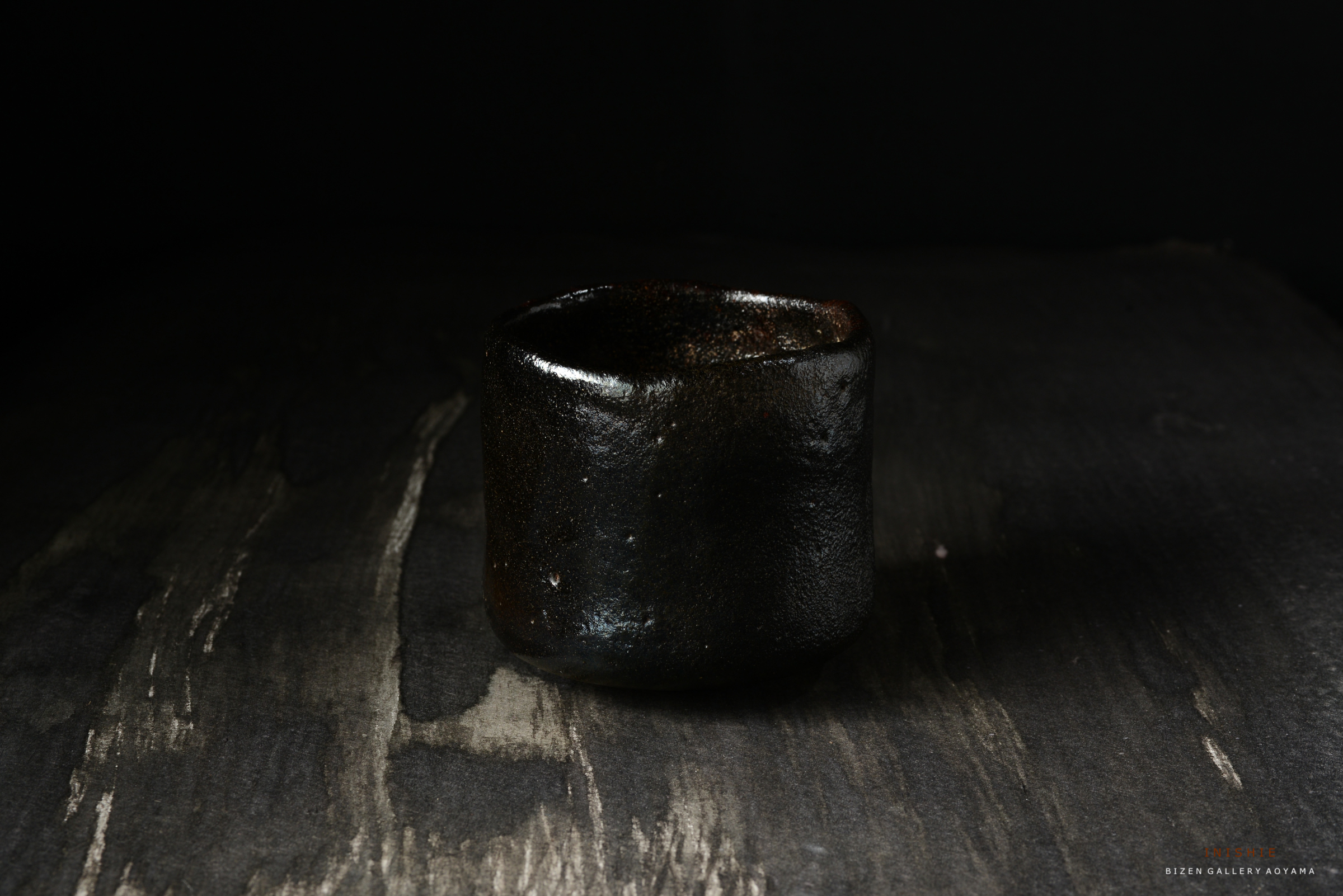 黒い陶器の茶碗が暗い背景の上に置かれている