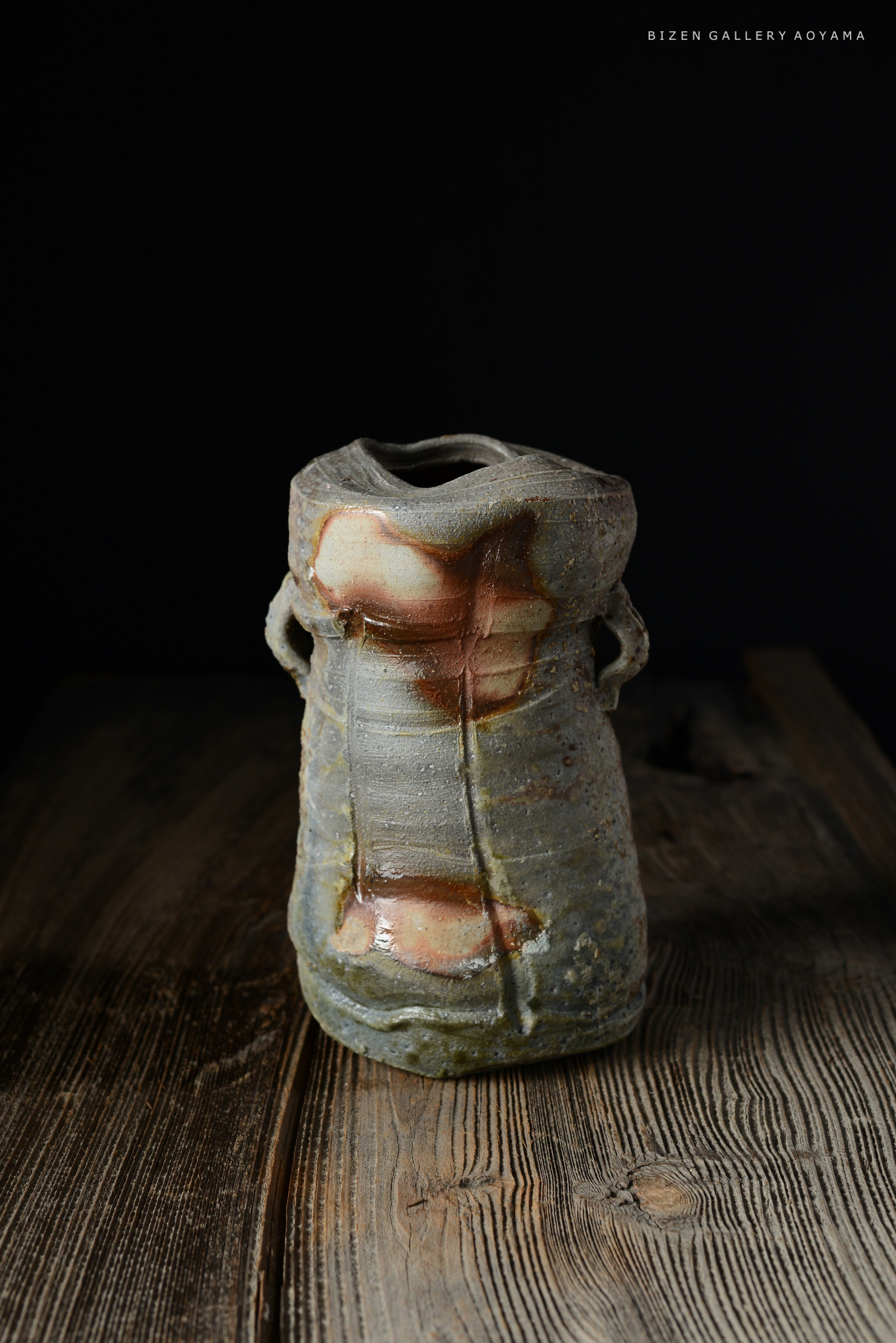 壺の形をしたビゼン焼きの陶器、暗い背景に置かれ、木のテーブルの上に置かれている