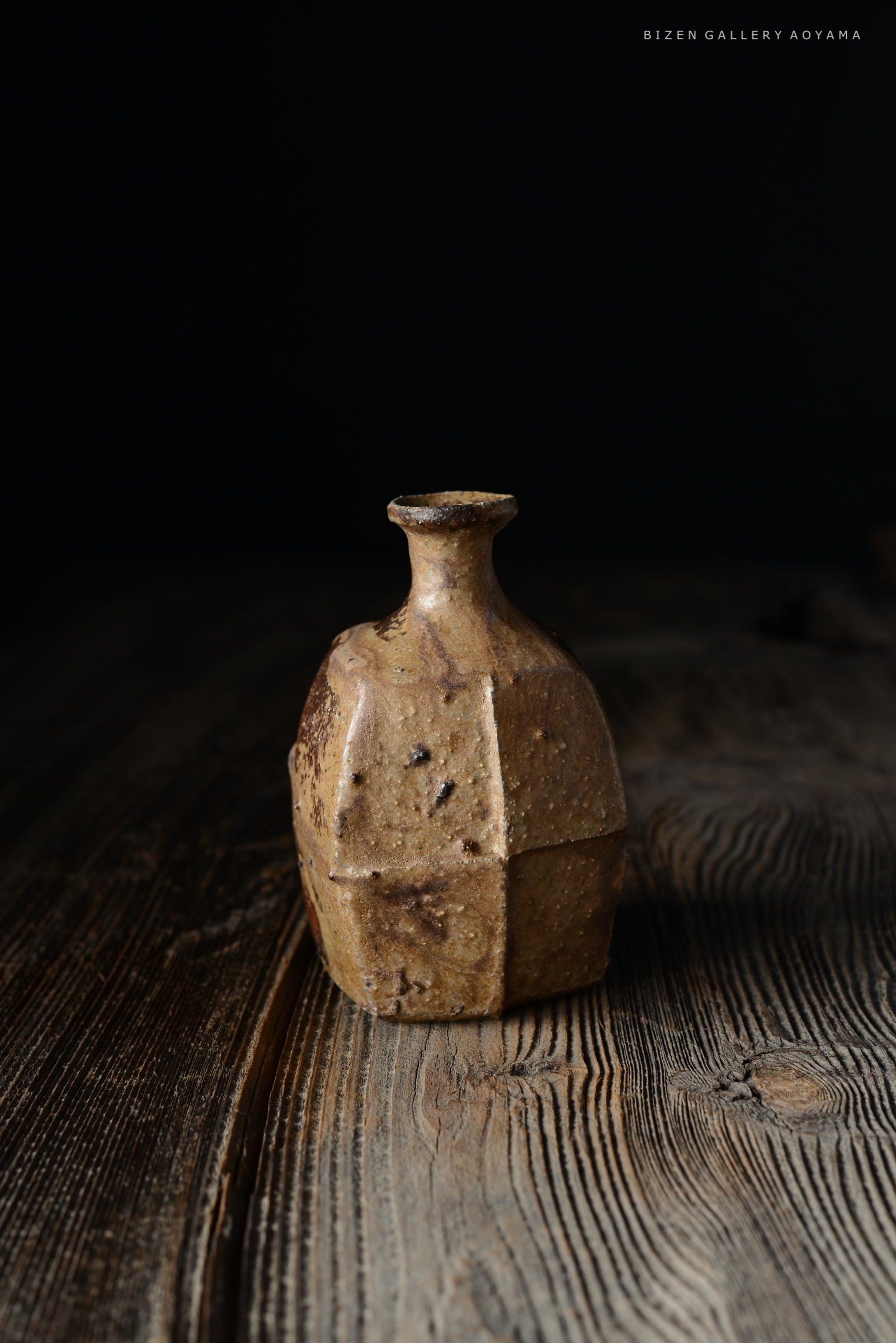 暗い背景の前に置かれた独特の形の陶器の壺