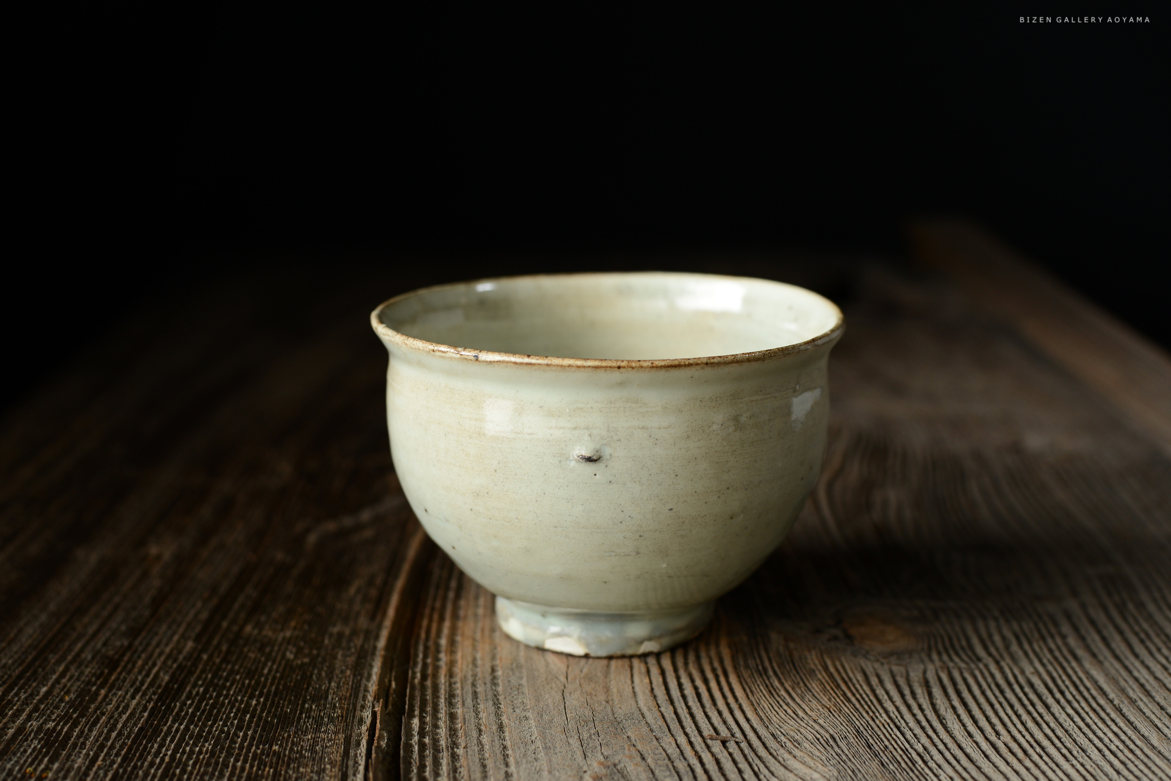 木のテーブルの上に置かれた淡い色の陶器の茶碗
