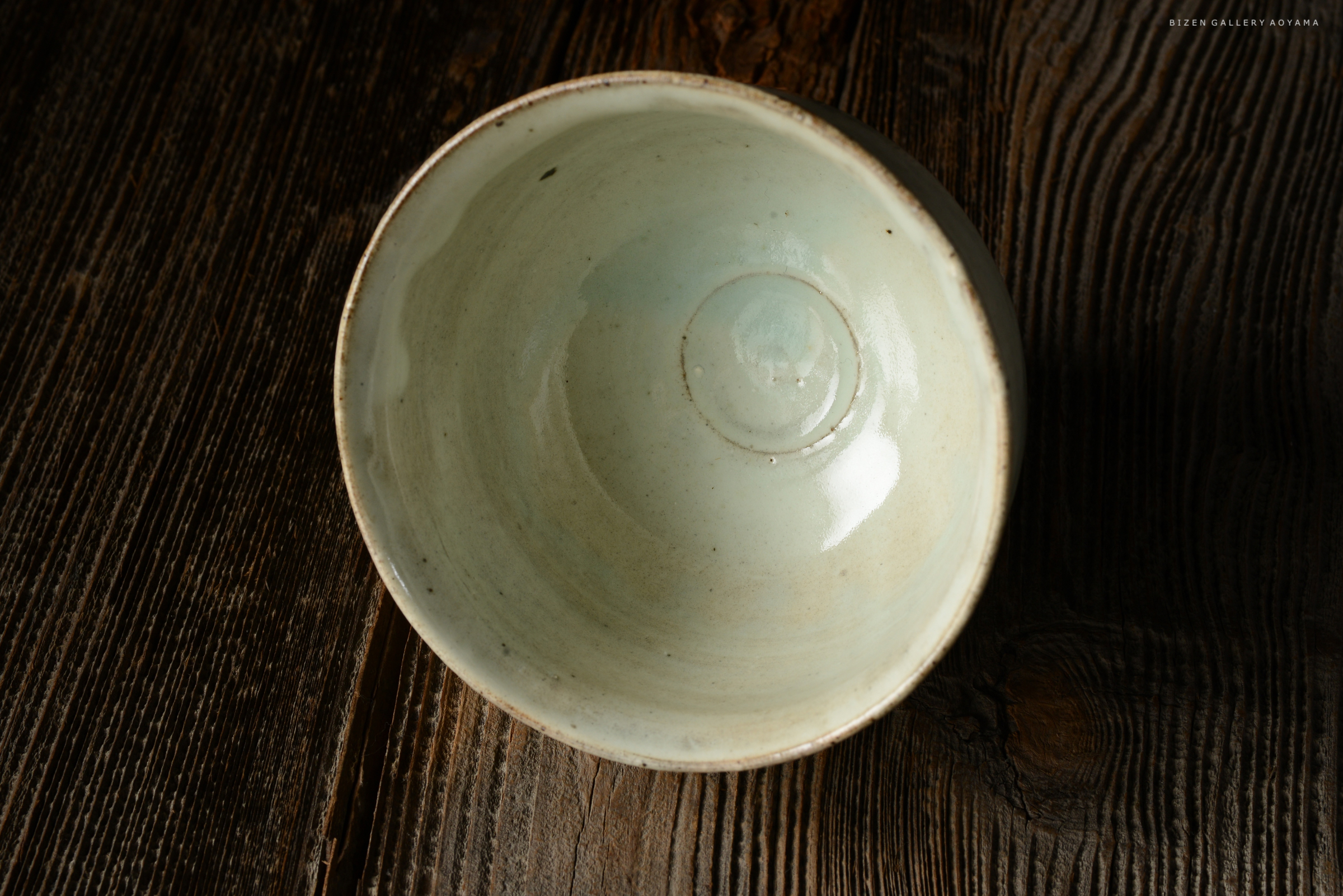 淡い青色の陶器のボウルが木のテーブルの上に置かれている