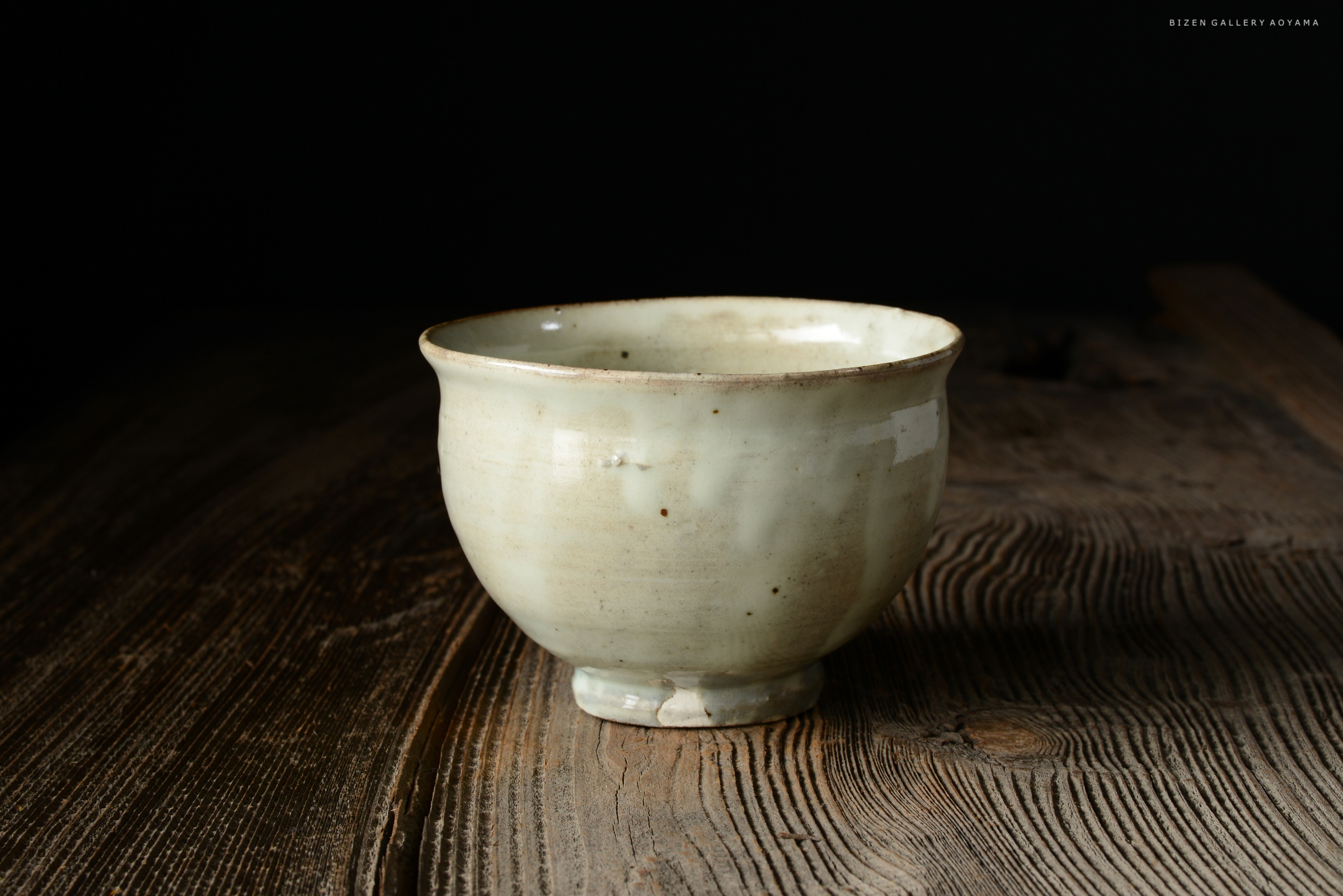 木のテーブルの上に置かれた青磁の茶碗。