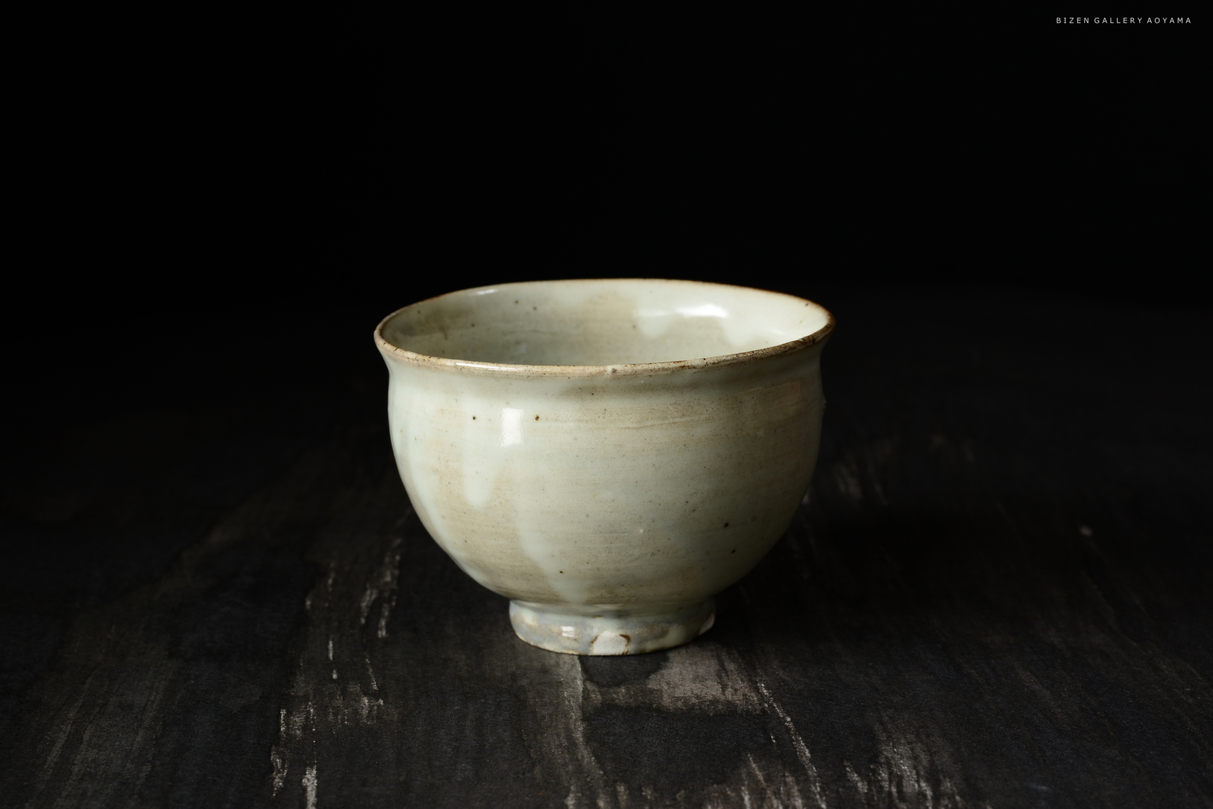 黒い背景の上に置かれた淡い色の陶器の茶碗