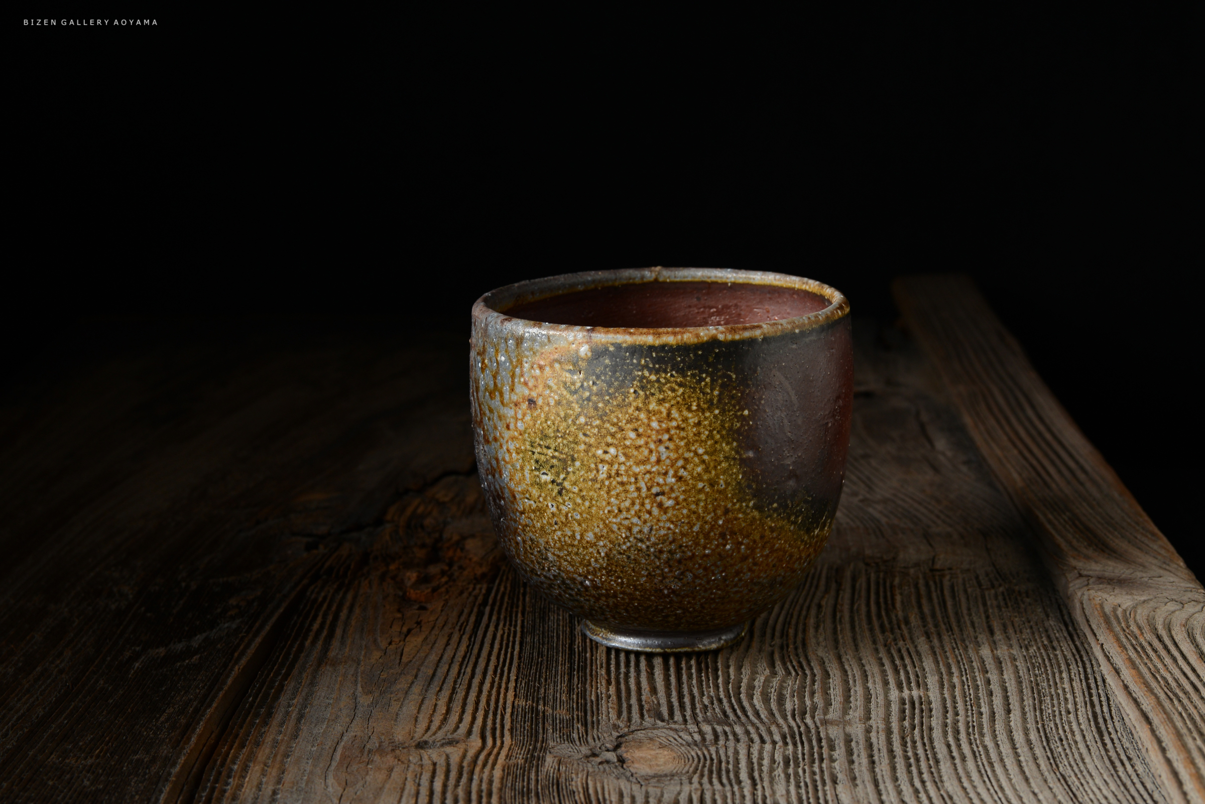黒の背景の前に置かれた、ユニークなデザインの陶器の杯